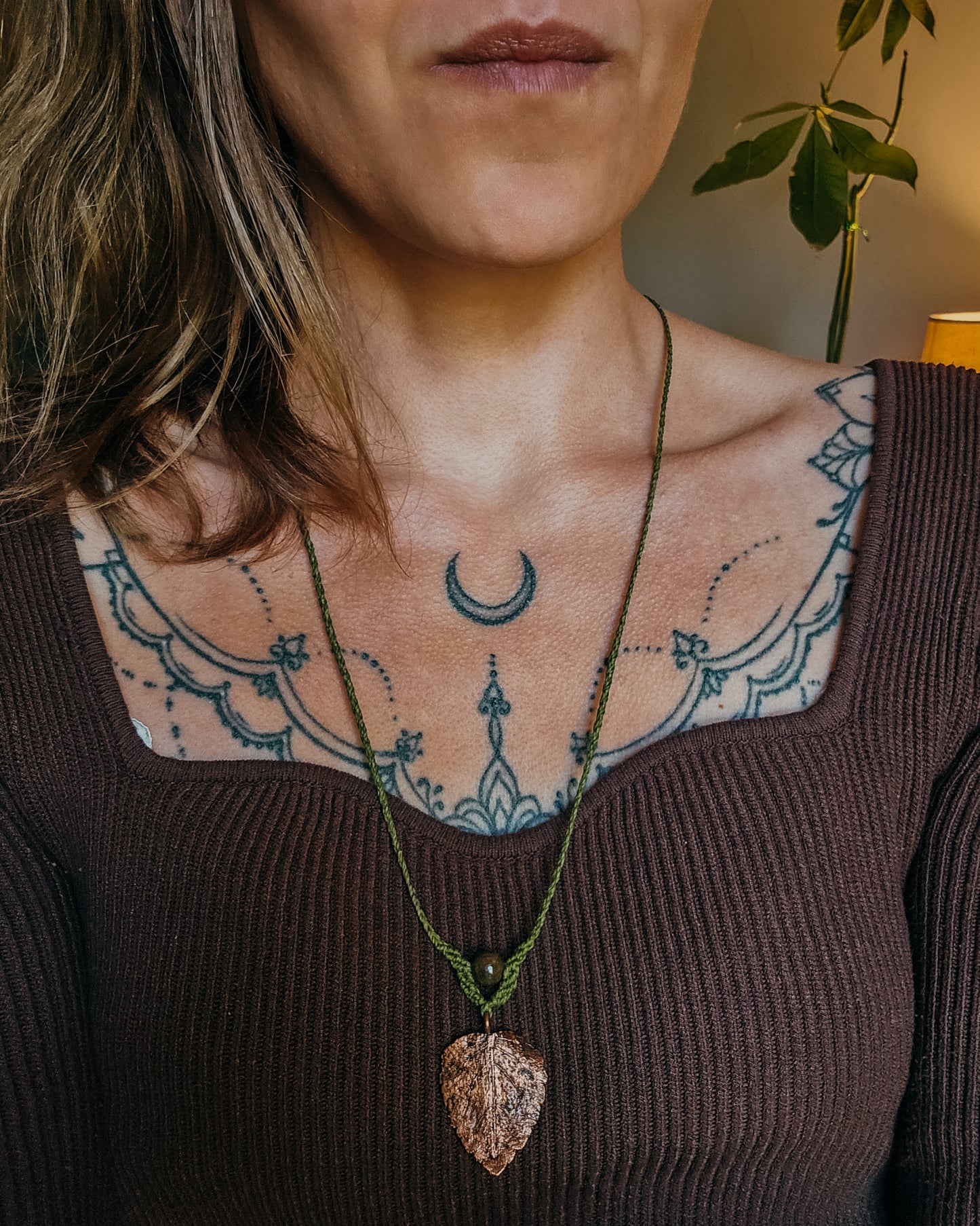 Woman wearing Nettle Spirit Scottish Botanical Amulet, a copper electroformed dead nettle leaf necklace featuring a natural Brown Jasper bead.