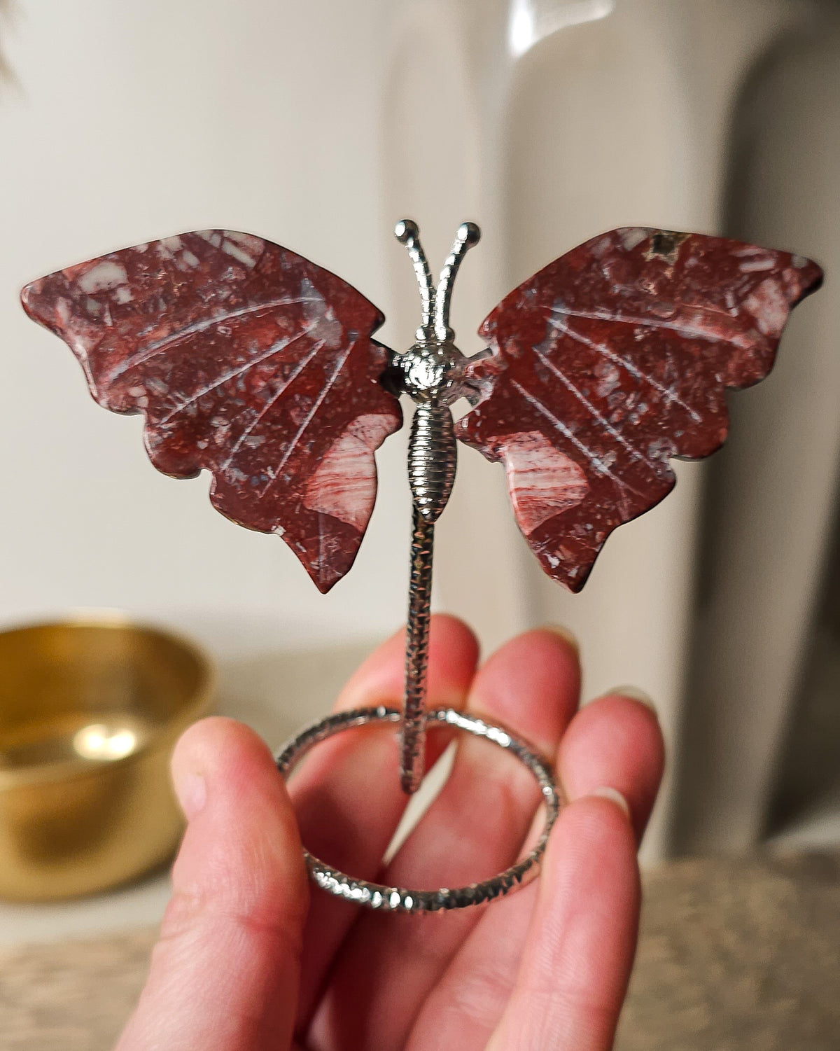 Red Jasper butterfly carving on a silver-tone metal stand, featuring deep brick-red colouring and natural white mineral patterns.