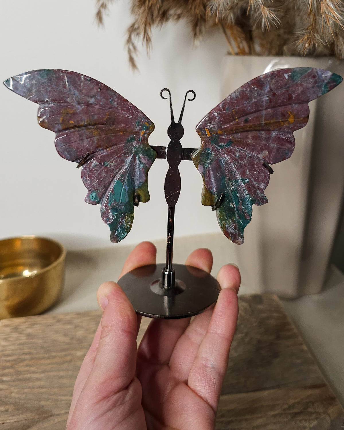 Jasper butterfly wings on a black metal stand, featuring earthy burgundy, green and golden natural patterns.