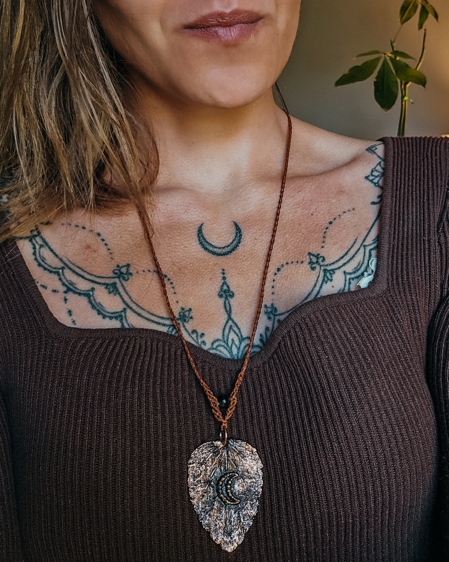 Copper electroformed botanical necklace worn by a woman, featuring a real dead nettle leaf captured in copper with crescent moon detail.