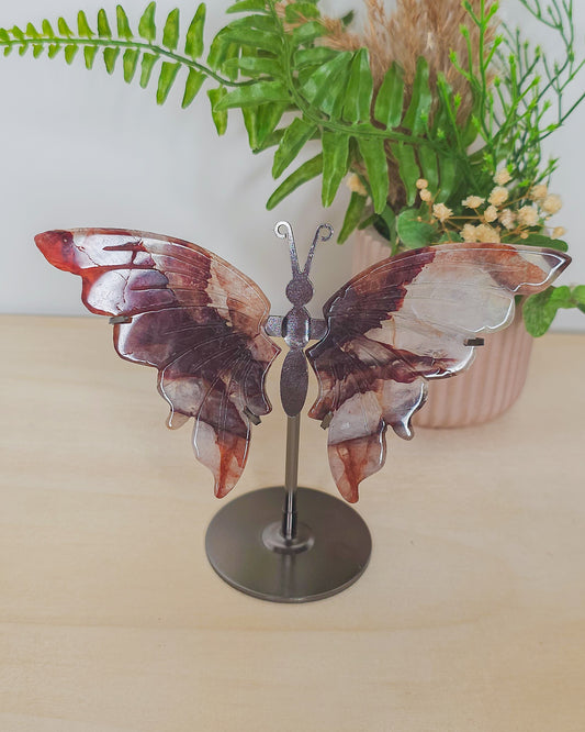 Fire Quartz butterfly wings on metal stand, featuring red Hematite inclusions in clear quartz, symbolizing transformation, strength, and focus.
