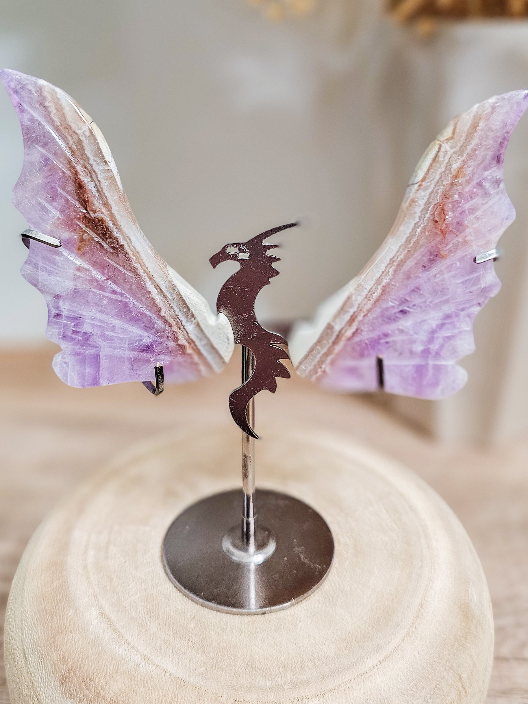 Pair of carved amethyst dragon wings on acrylic stand, showing violet crystal texture and mystical wing shape