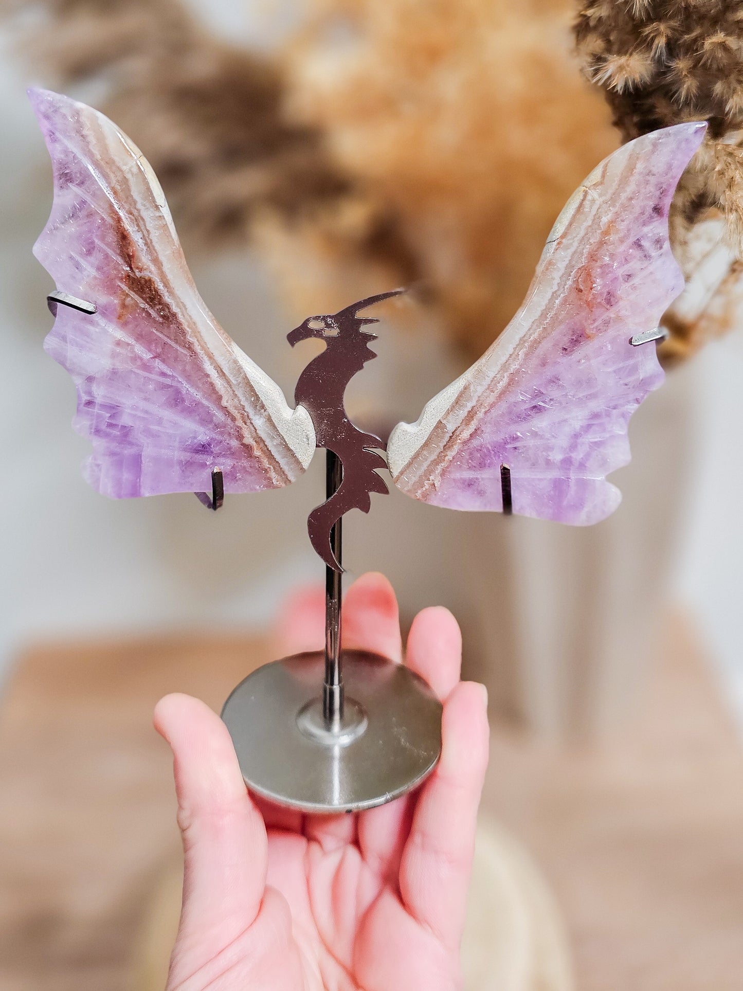 Violet amethyst dragon wings, carved with intricate detail, showing natural banding and crystal texture