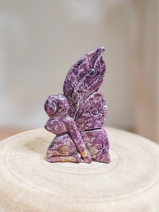 Charoite fairy carving in lavender to deep violet hues, showing intricate swirling patterns and delicate fairy shape