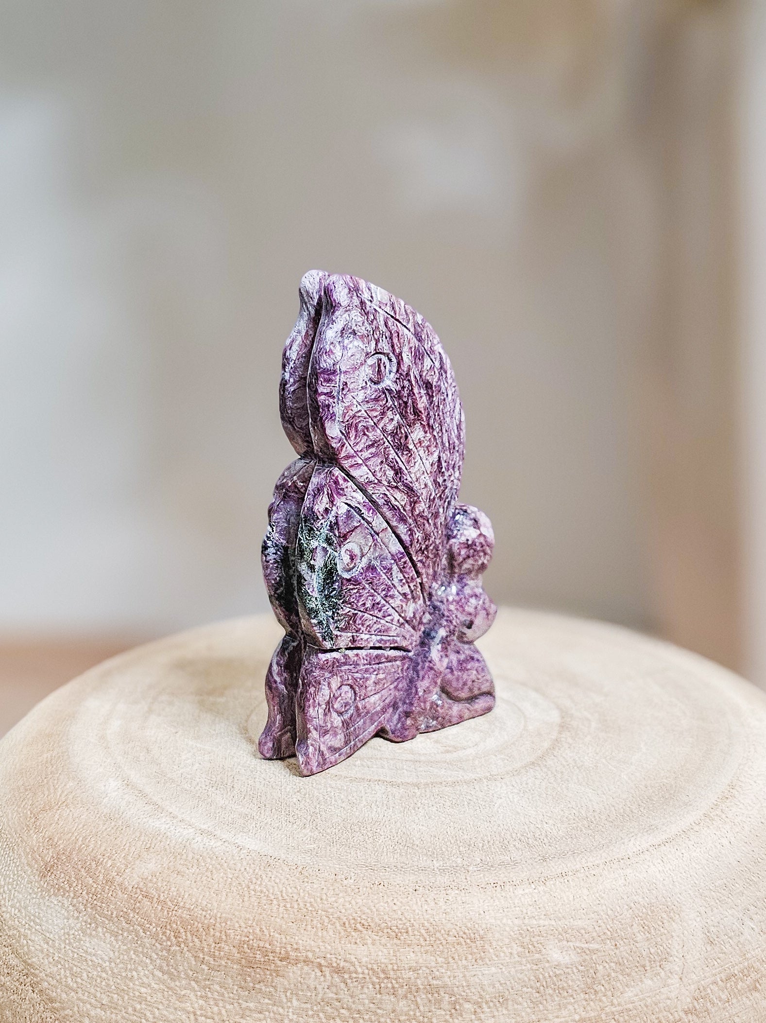 Close-up of carved Charoite fairy, highlighting swirling violet patterns and translucent crystal texture