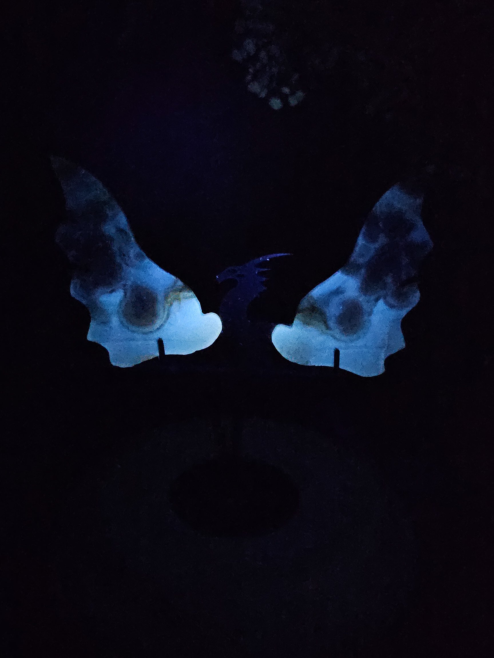 Close-up of carved Flower Agate dragon wings, showing intricate crystal texture and subtle fluorescence under light