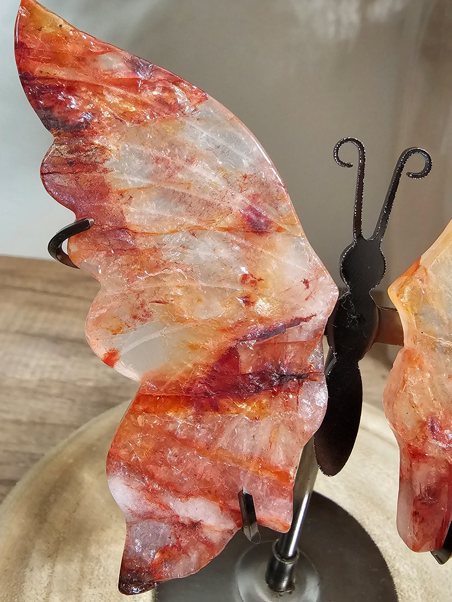 Butterfly-shaped stone with a metal stand on a neutral background