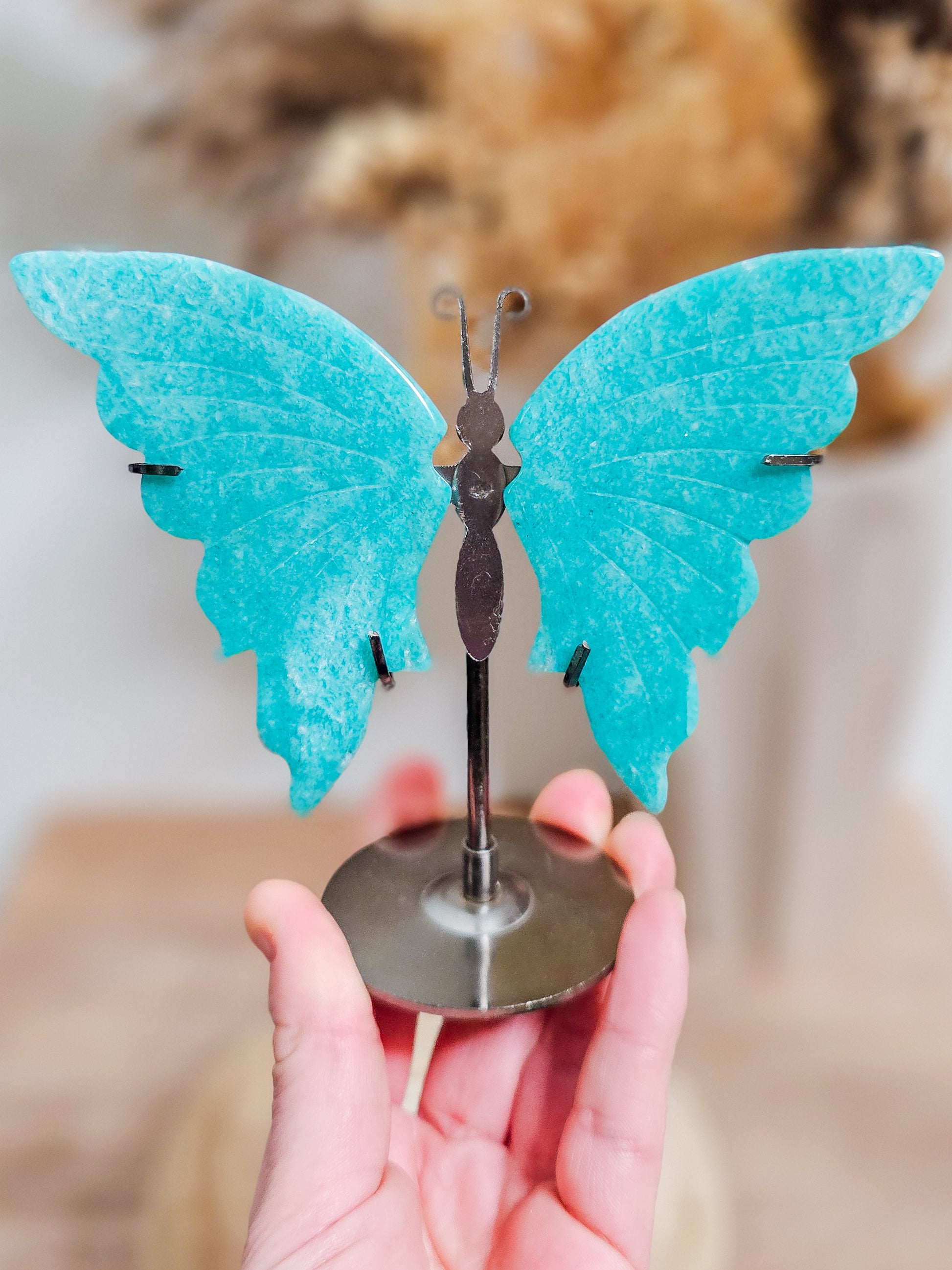 Carved amazonite butterfly wings on display stand, showing soft turquoise tones and natural stone patterns