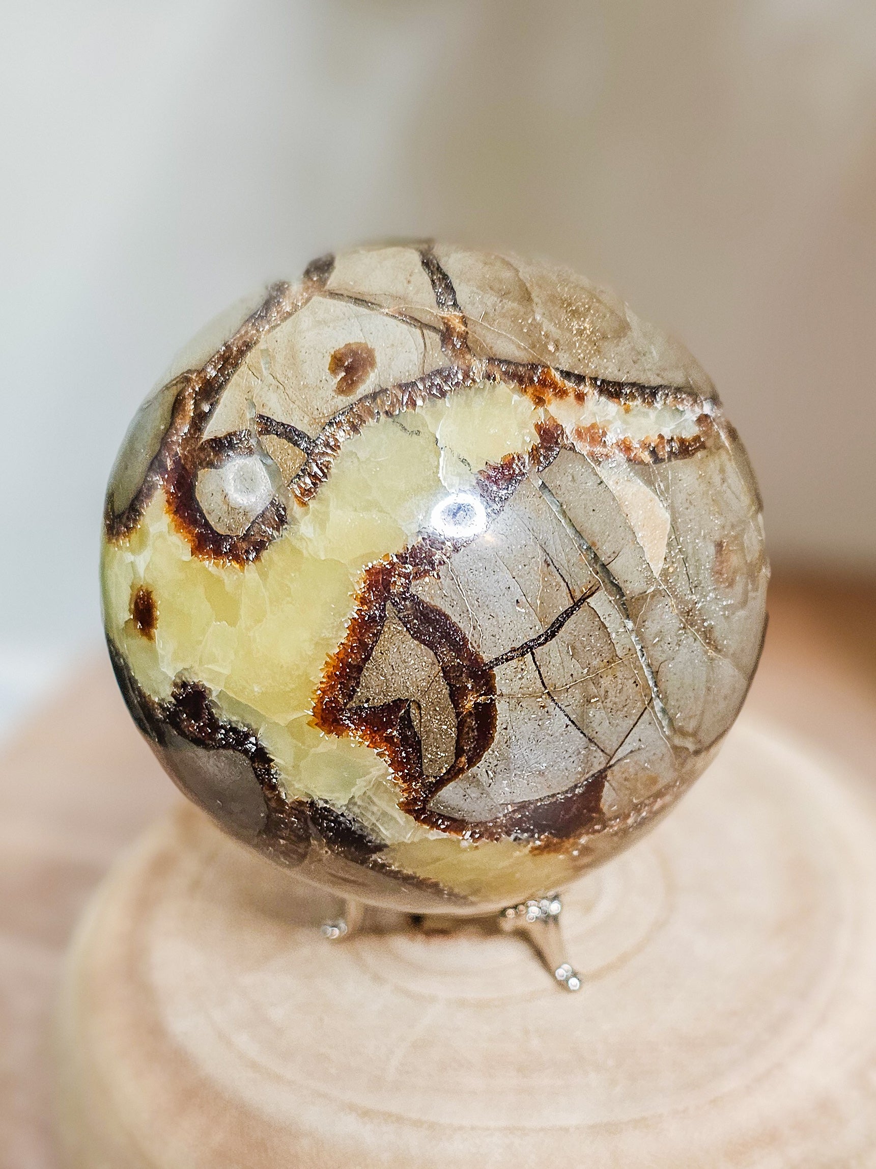 Polished Septarian sphere on stand, glowing under UV light to reveal fluorescent Calcite