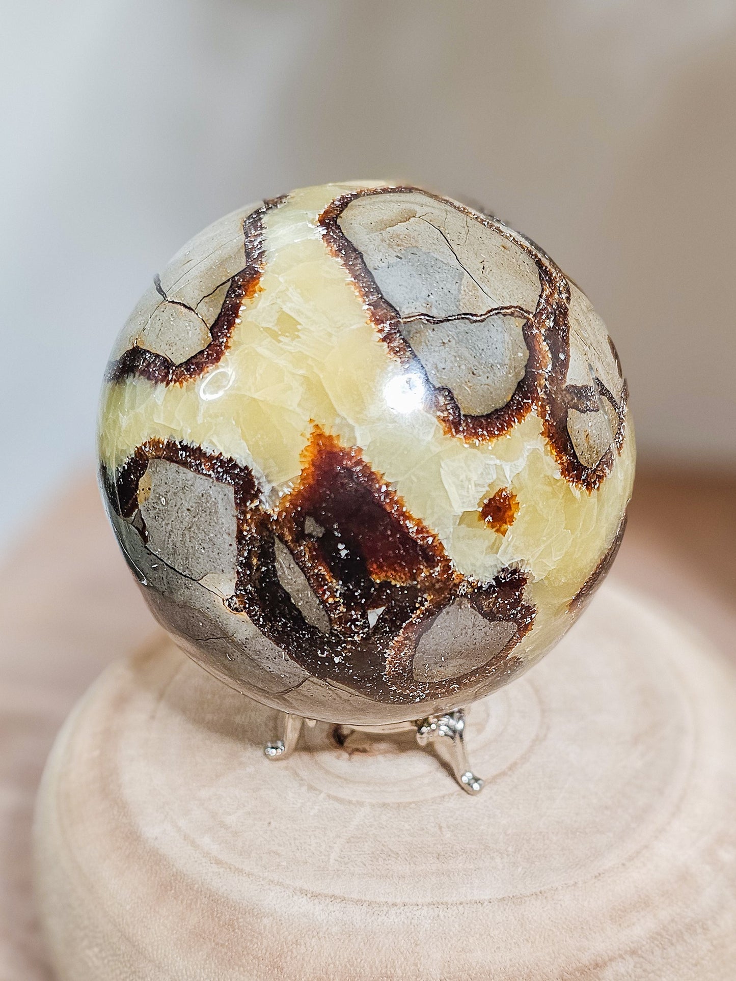 Fluorescent Septarian sphere on stand, polished brown and yellow stone with natural crackled patterns and glowing Calcite veins