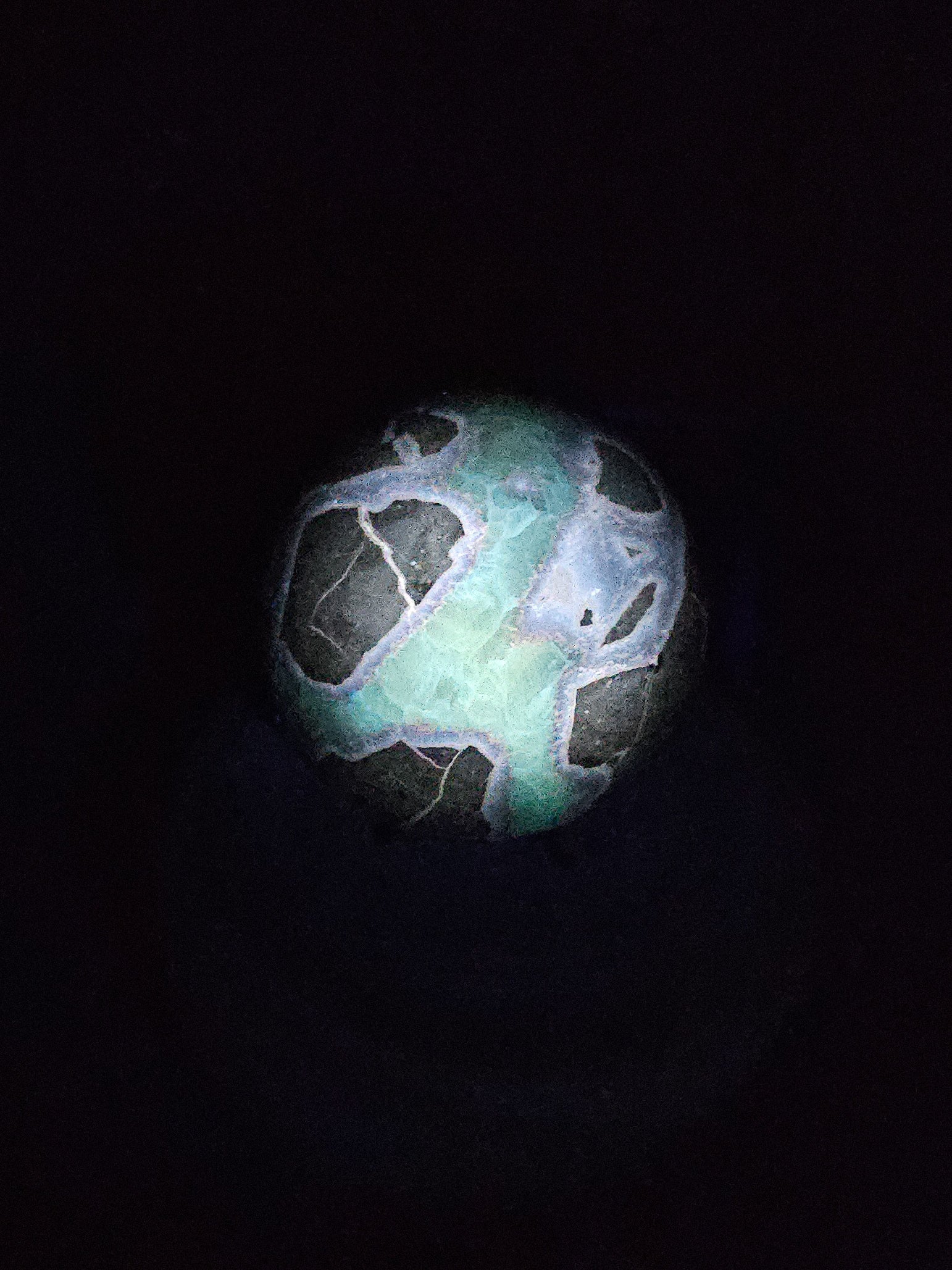 Polished Septarian sphere on stand, glowing under UV light to reveal fluorescent Calcite