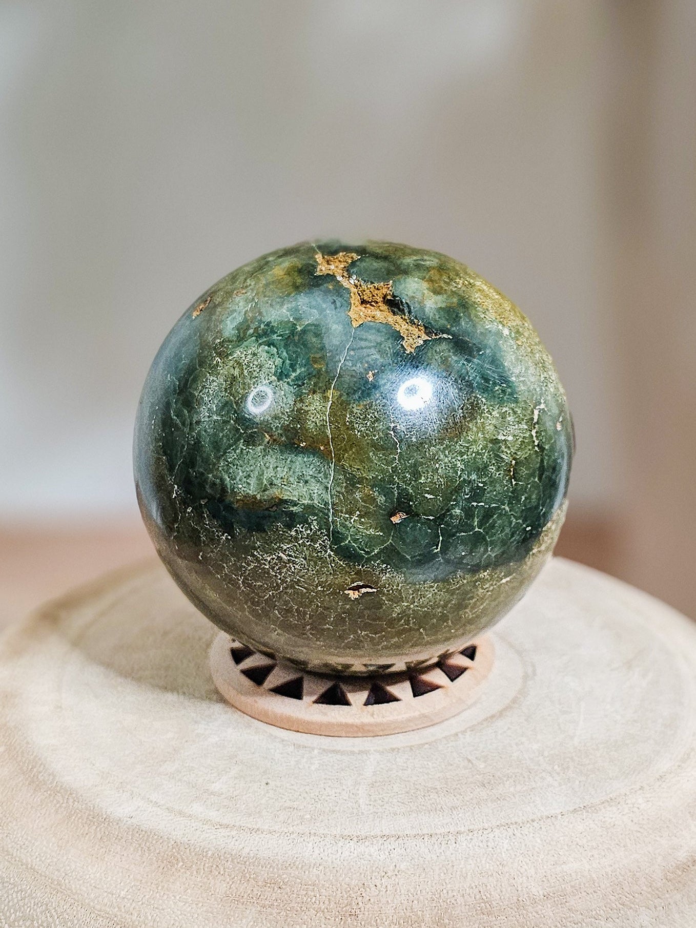 Sea Jasper sphere with natural open cavities and cracks, polished brown, beige, and green stone on stand