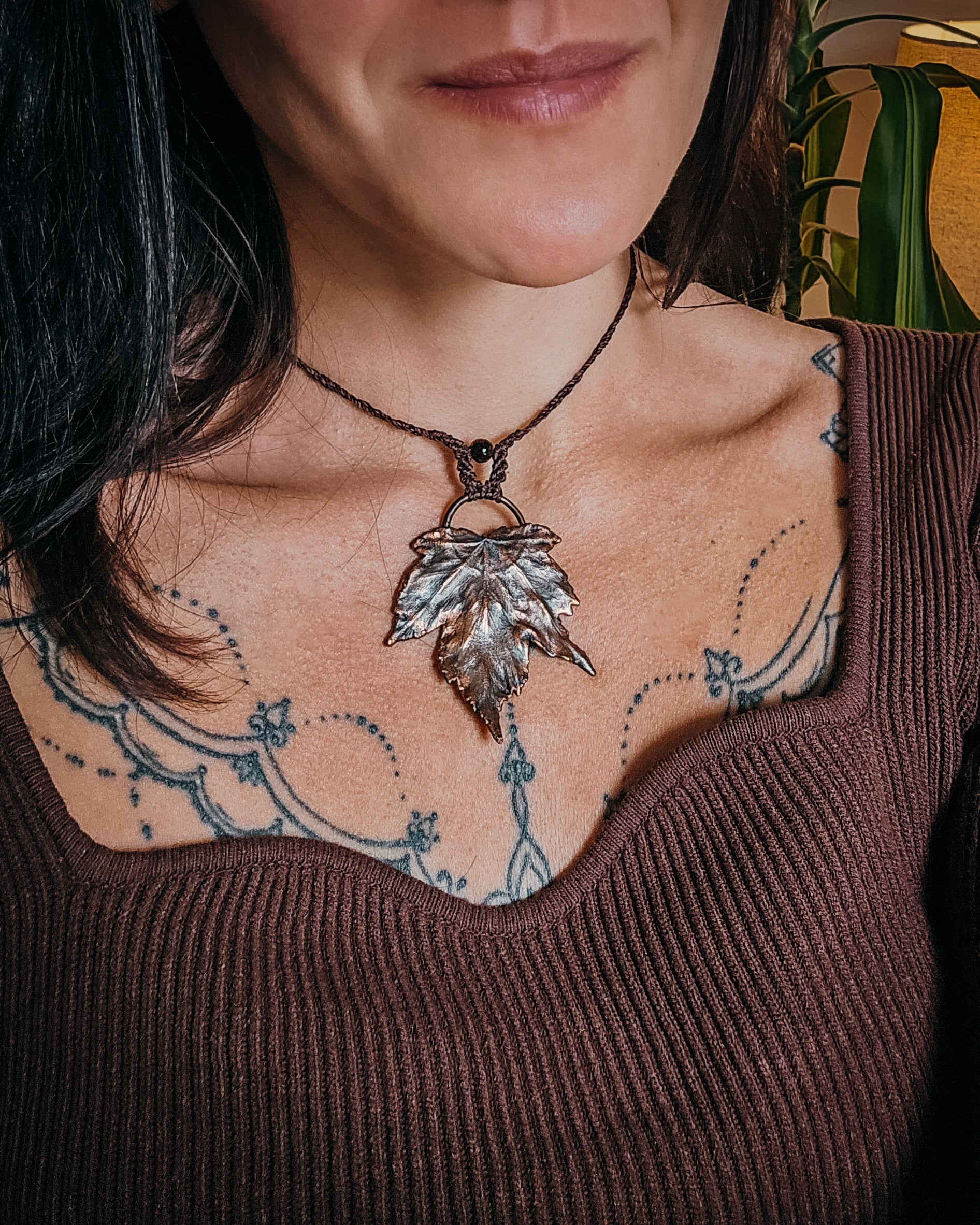 Person wearing a Handmade Copper electroformed Necklace with maple leaf pendant, macrame and Tiger's Eye bead 