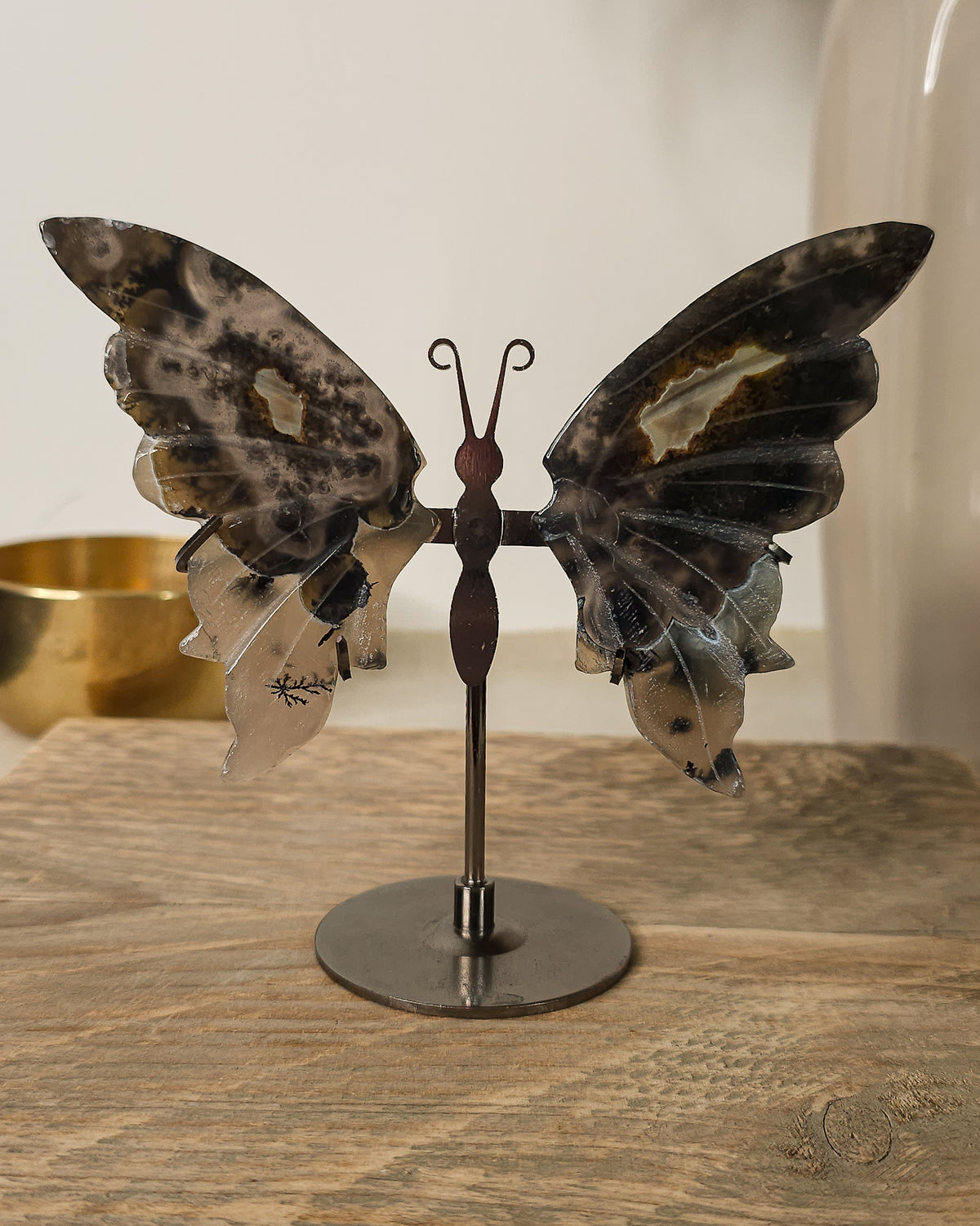 Fluorescent Volcano Agate butterfly wings with natural dendritic inclusions on a black metal stand, glowing green under UV light.