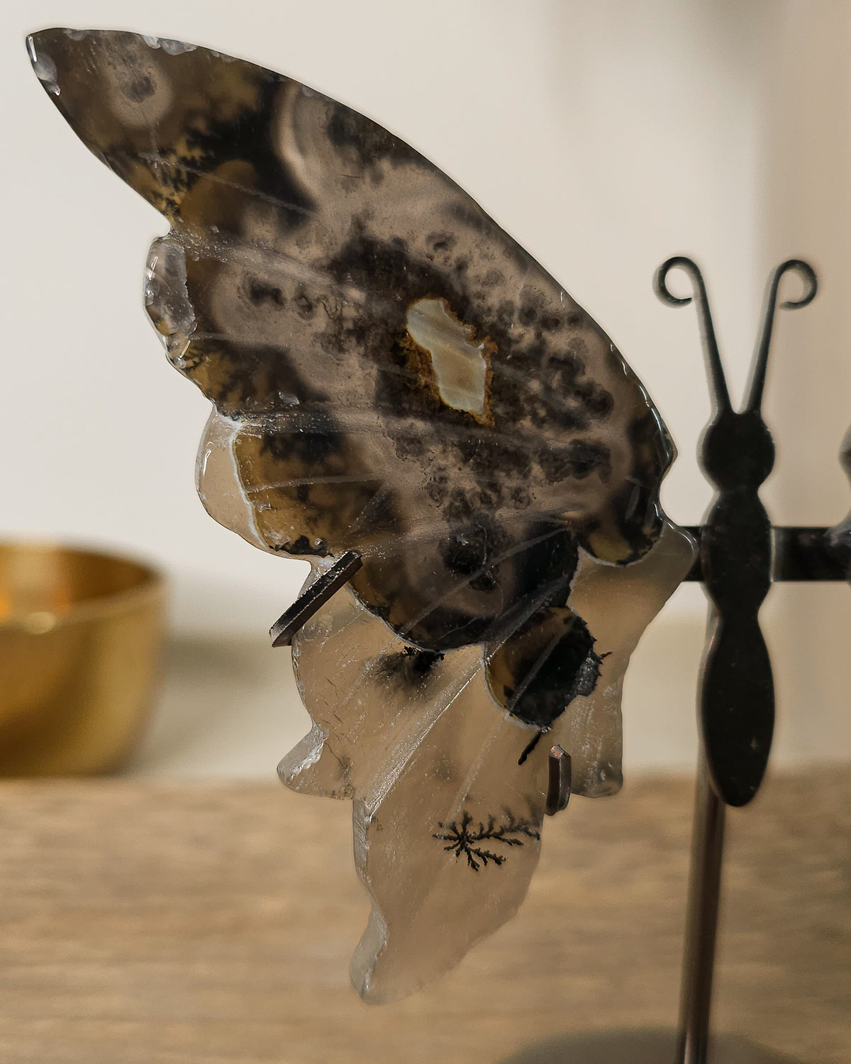 Fluorescent Volcano Agate butterfly wings with natural dendritic inclusions on a black metal stand, glowing green under UV light.