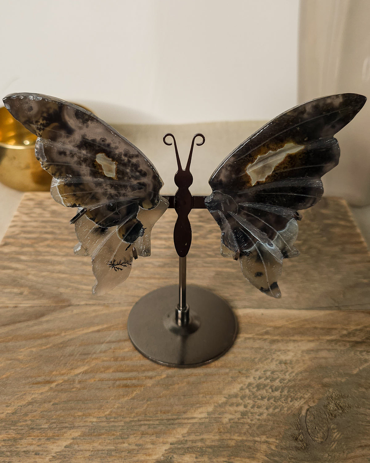 Fluorescent Volcano Agate butterfly wings with natural dendritic inclusions on a black metal stand, glowing green under UV light.