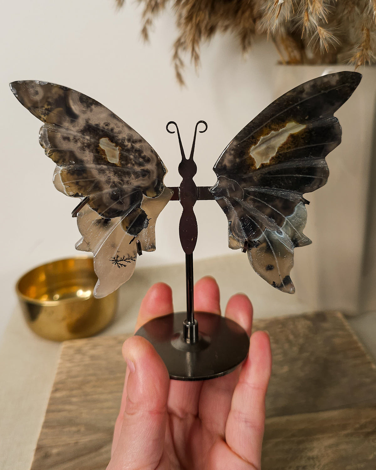 Fluorescent Volcano Agate butterfly wings with natural dendritic inclusions on a black metal stand, glowing green under UV light.