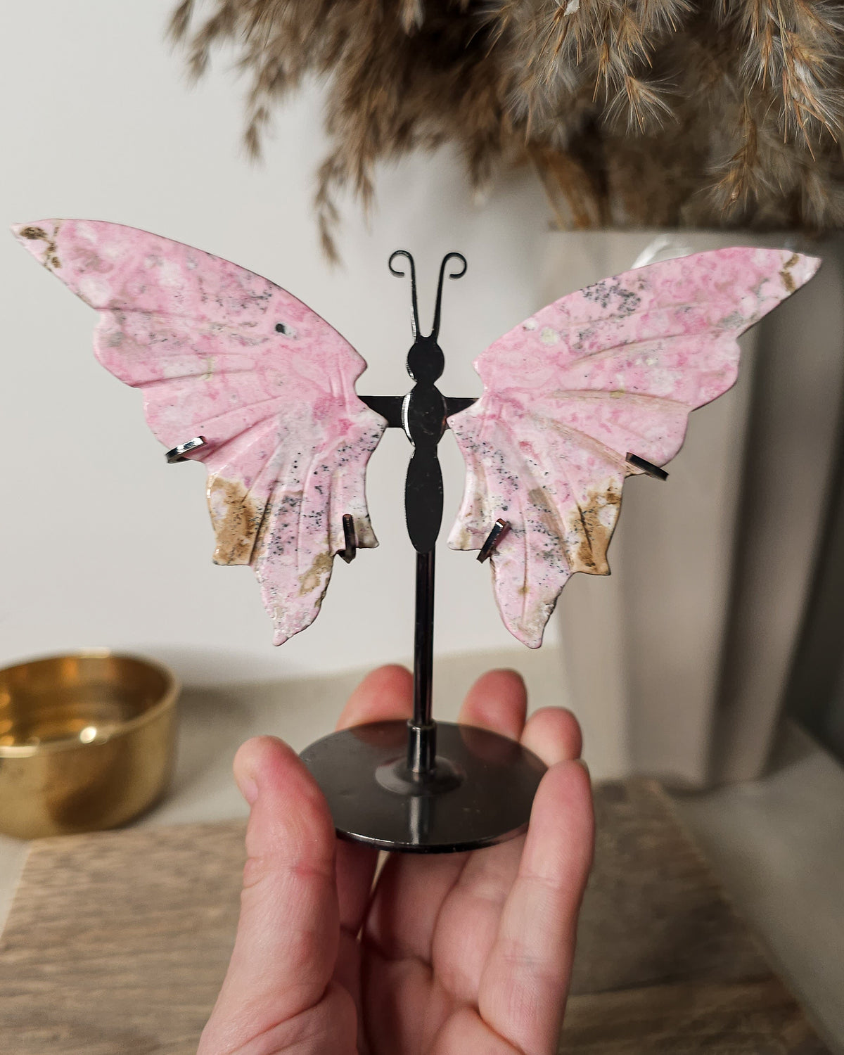 Peruvian Rhodonite crystal butterfly wings on a metal stand, with unique pink and dark markings. A meaningful gift or addition to your crystal collection.
