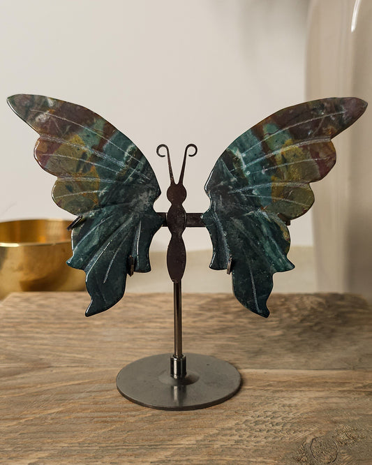 Jasper butterfly wings on a black metal stand, featuring deep green, earthy brown and golden natural patterns.