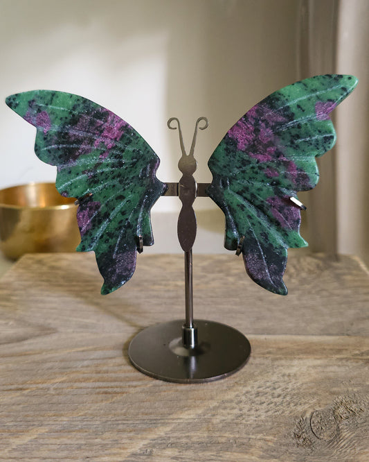 Ruby in Zoisite butterfly wings with fluorescent Ruby inclusions on a black metal stand, glowing vivid pink-red under UV light.