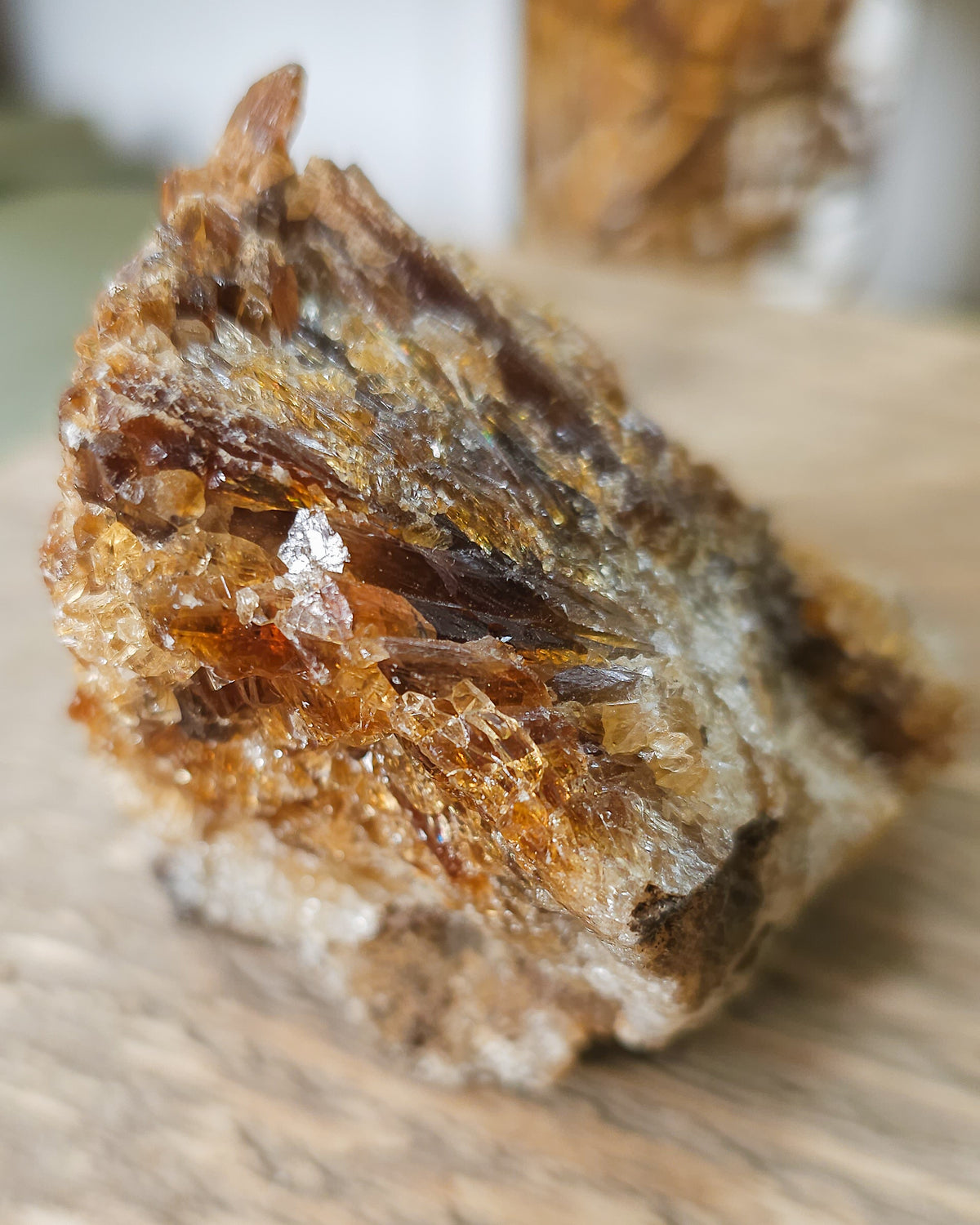 Mineral Amber Calcite specimen on a wooden surface with a blurred indoor background