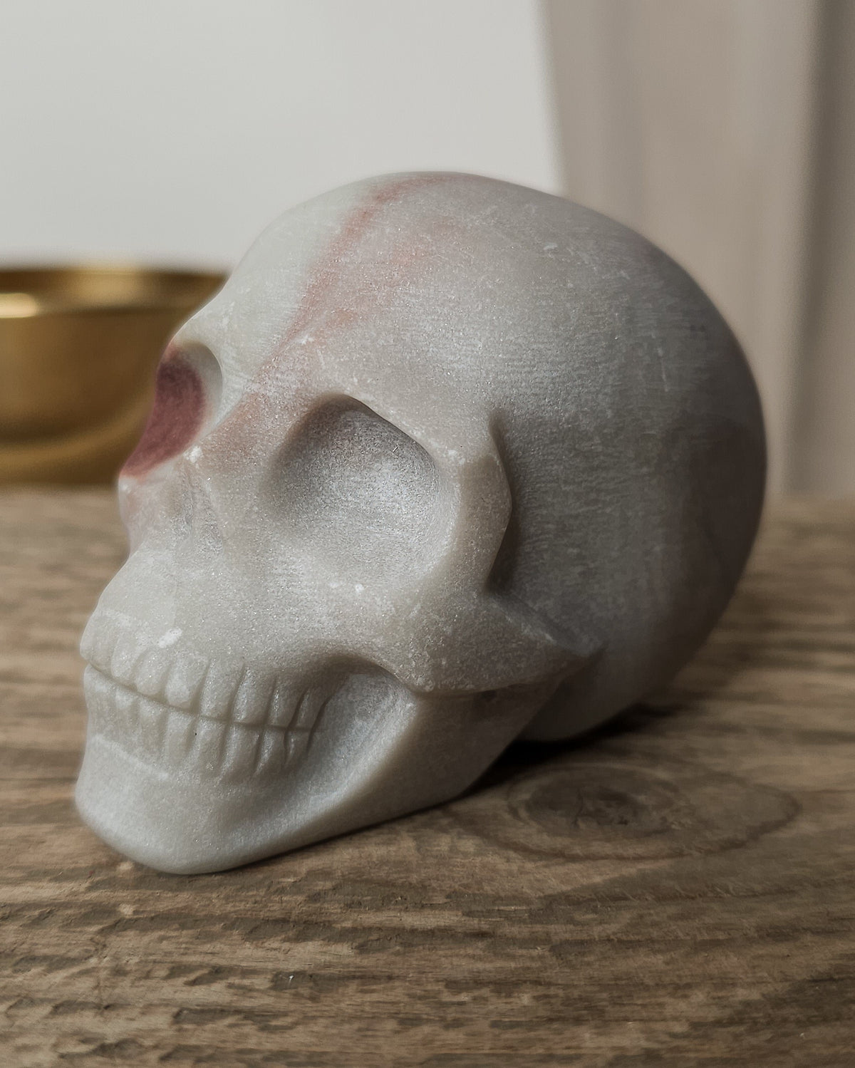 Mookaite crystal skull carving with natural burgundy, dusty pink, cream and grey patterns, polished finish and detailed teeth.