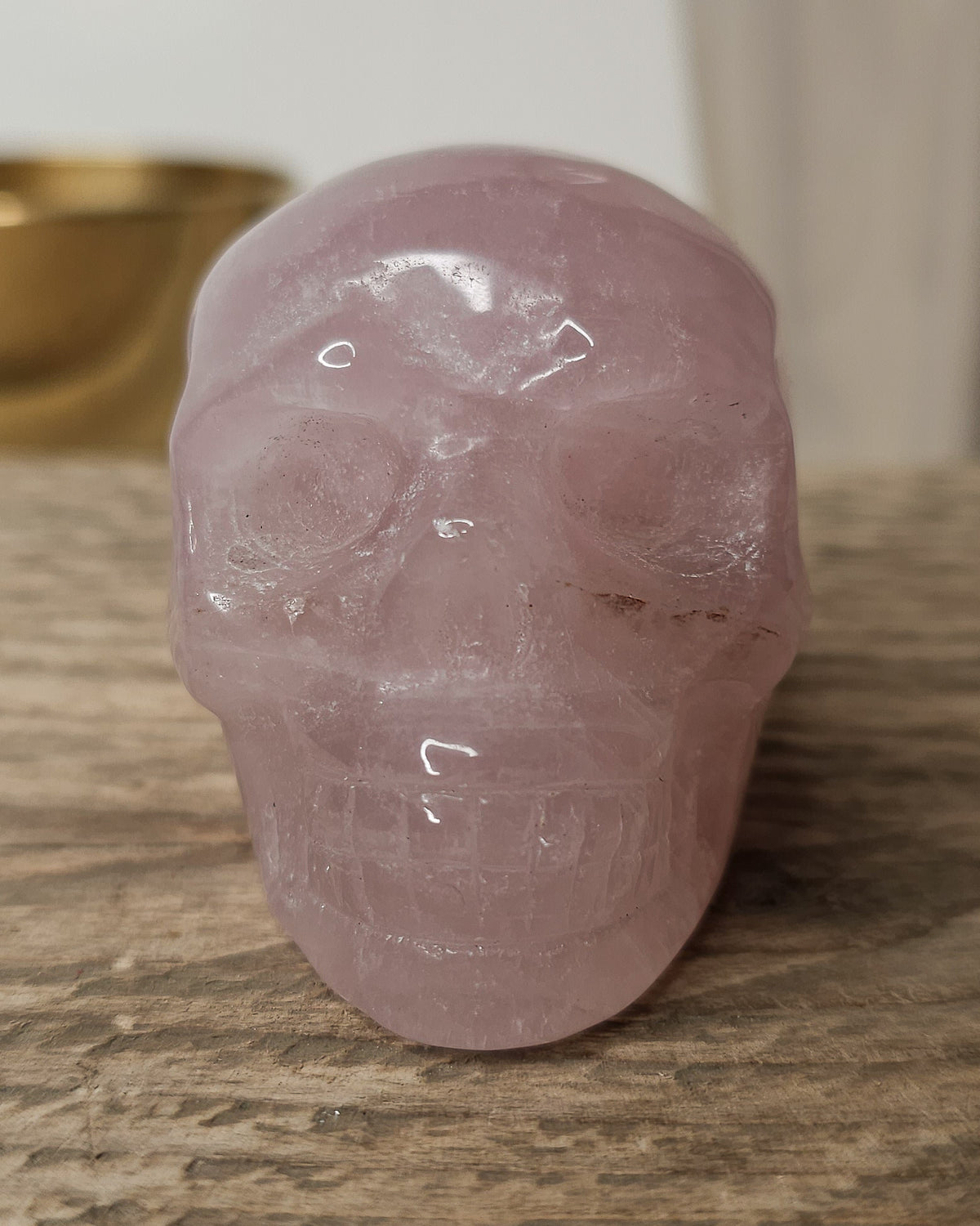 Rose Quartz crystal skull carving with soft pink tones and natural cloudy patterns, polished finish, displayed as a decorative crystal piece.