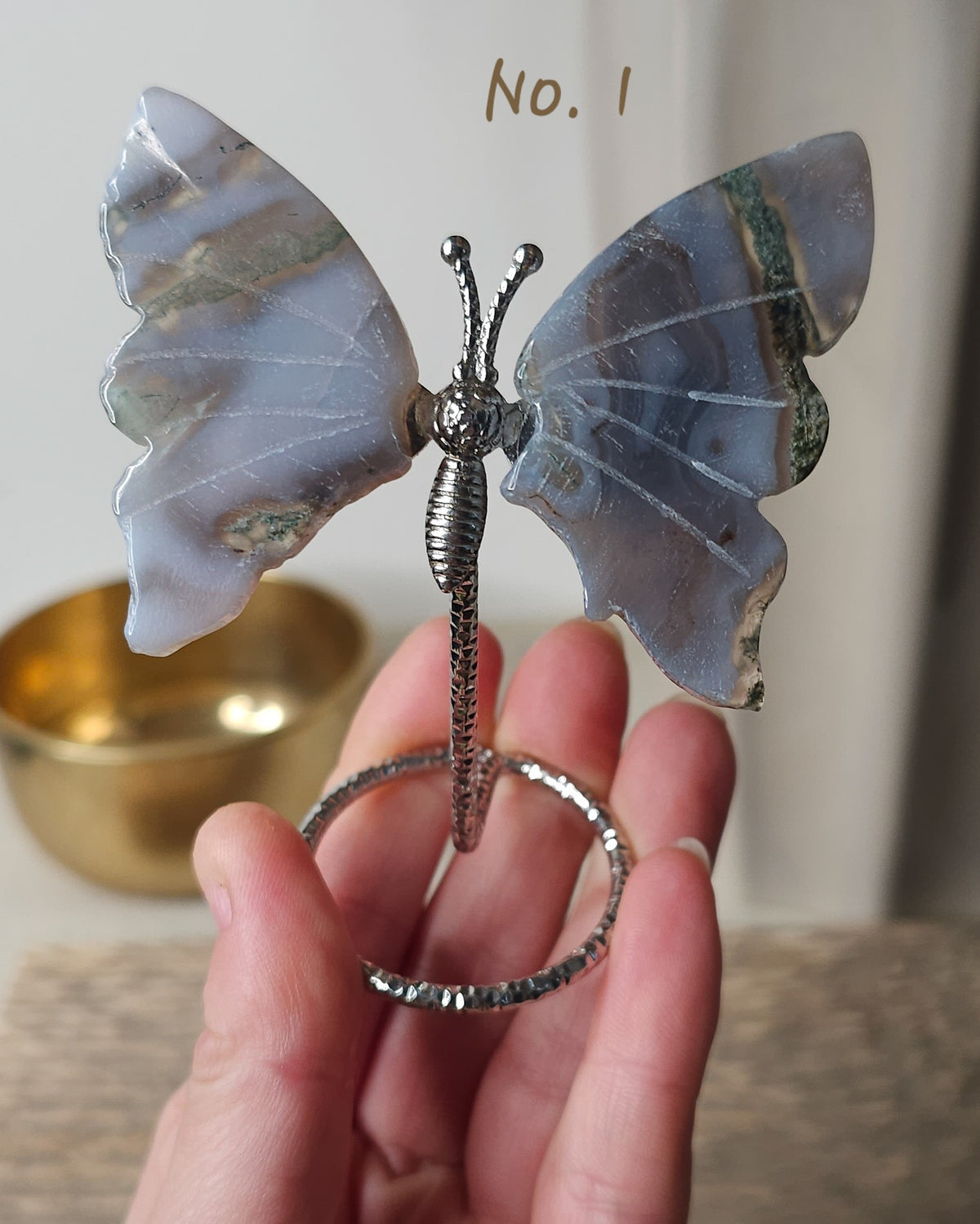 Moss Agate crystal butterfly wings on a stand with natural green moss-like inclusions. A nature-inspired decorative piece and meaningful gift for new beginnings.
