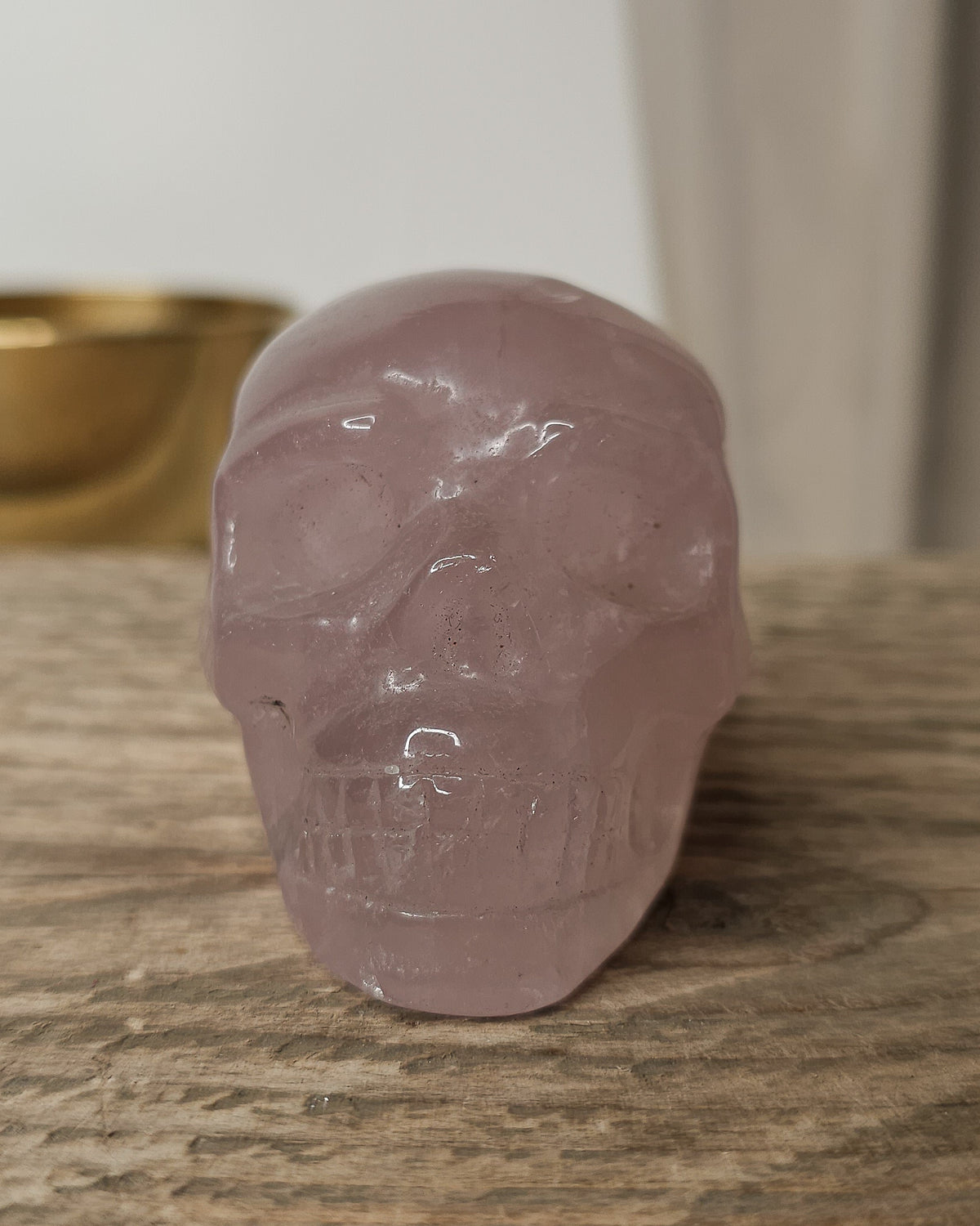 Rose Quartz crystal skull carving with soft pink tones and natural cloudy patterns, polished finish, displayed as a decorative crystal piece.