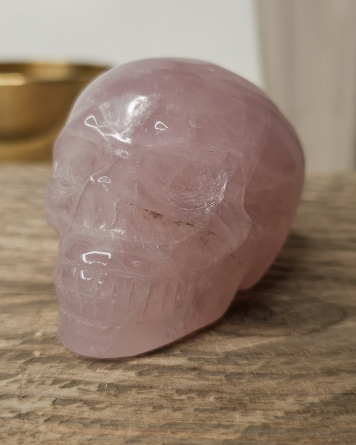 Rose Quartz crystal skull carving with soft pink tones and natural cloudy patterns, polished finish, displayed as a decorative crystal piece.