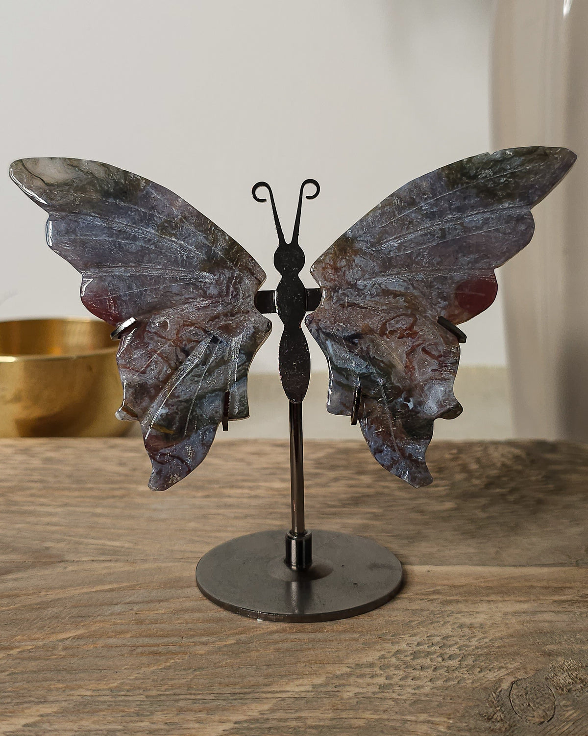 Moss Agate butterfly wings on a black metal stand, featuring natural grey, green, brown and reddish patterns.
