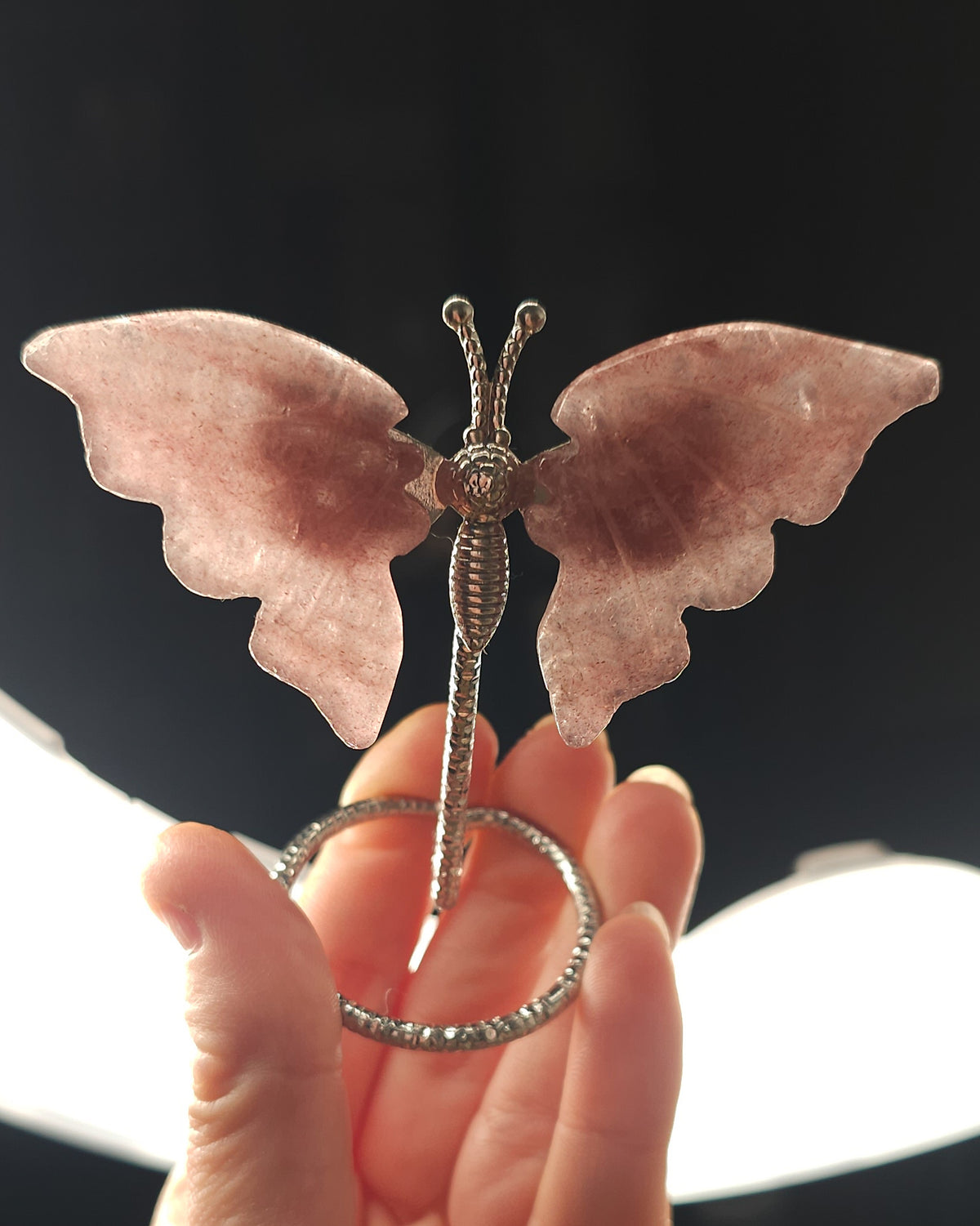 Strawberry Quartz butterfly carving on a silver metal stand, featuring soft rosy pink tones and delicate natural inclusions.