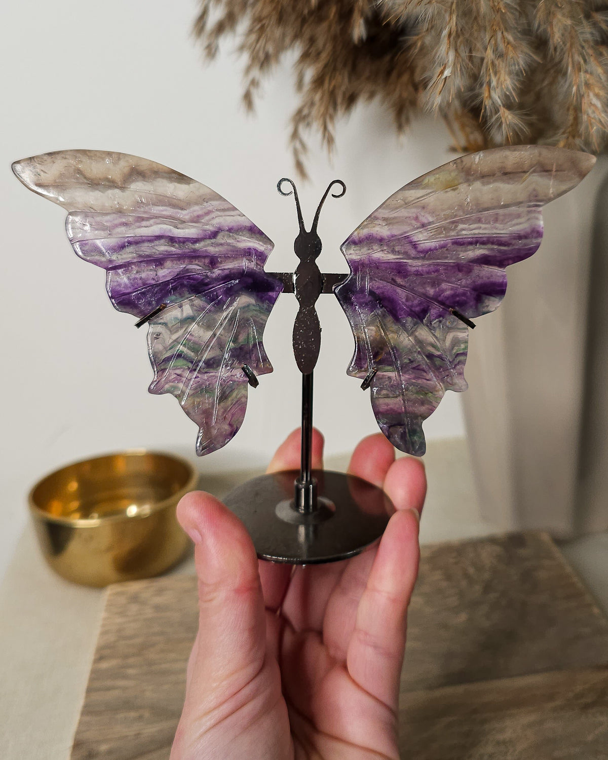 Fluorite crystal butterfly wings on a stand, with purple, green and golden tones. A beautiful display piece and meaningful gift for new beginnings.
