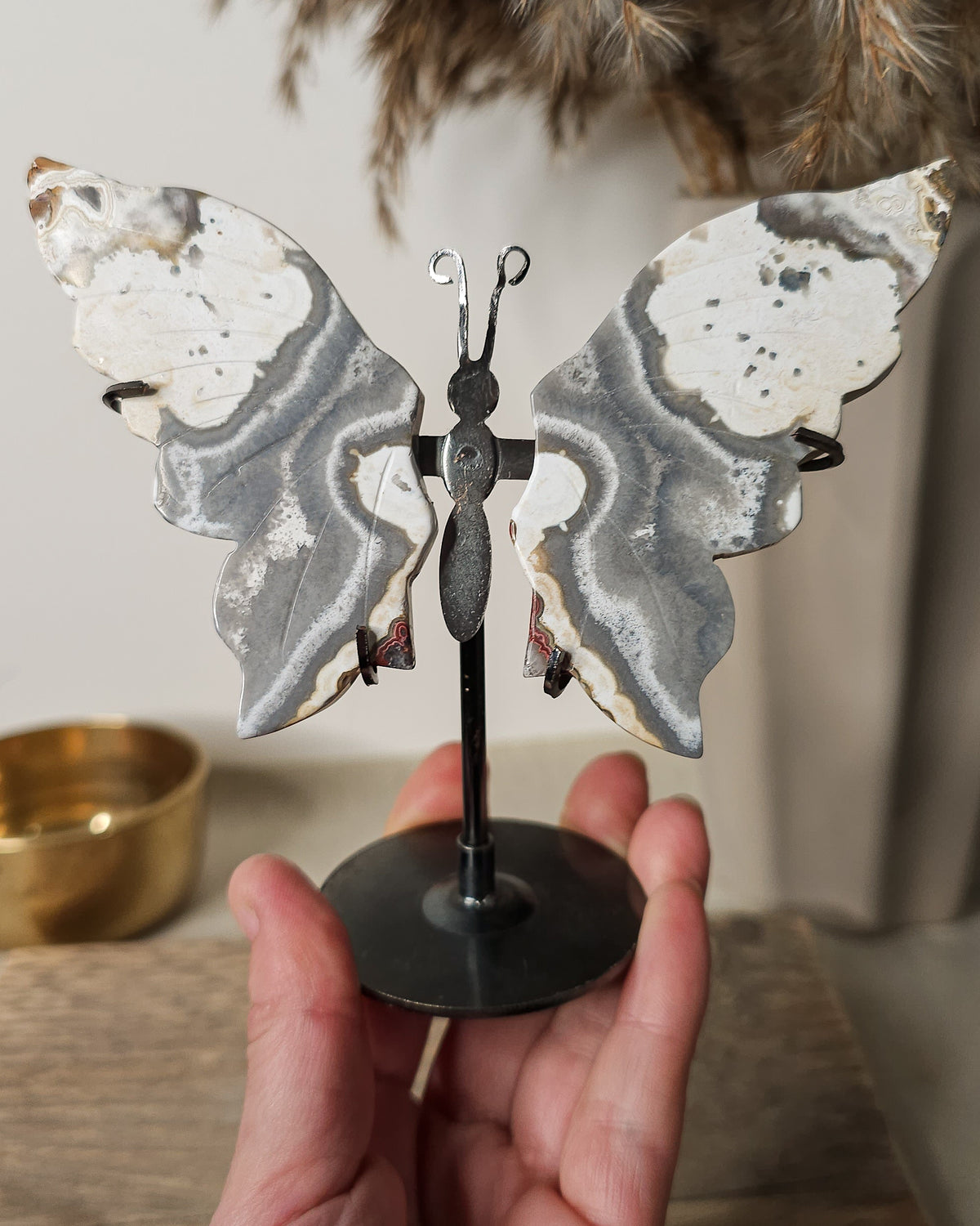 Grey and white Agate butterfly wings displayed on a metal stand, featuring soft natural banding and cloudy patterns.