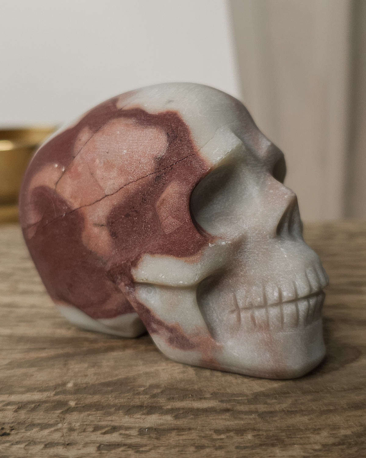 Mookaite crystal skull carving with natural burgundy, dusty pink, cream and grey patterns, polished finish and detailed teeth.