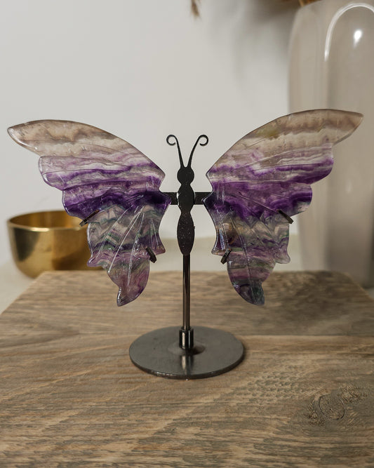 Fluorite crystal butterfly wings on a stand, with purple, green and golden tones. A beautiful display piece and meaningful gift for new beginnings.
