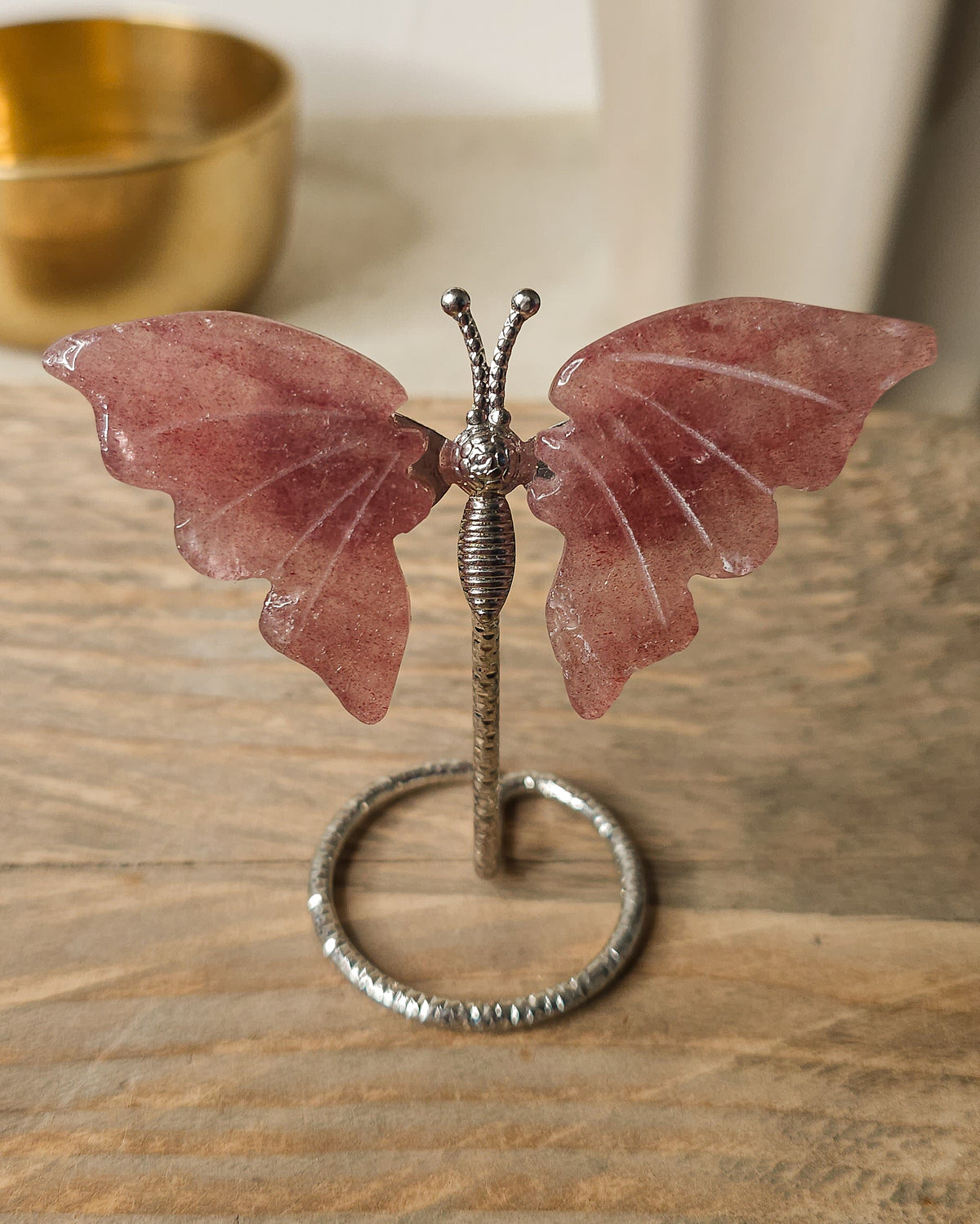 Strawberry Quartz butterfly carving on a silver metal stand, featuring soft rosy pink tones and delicate natural inclusions.