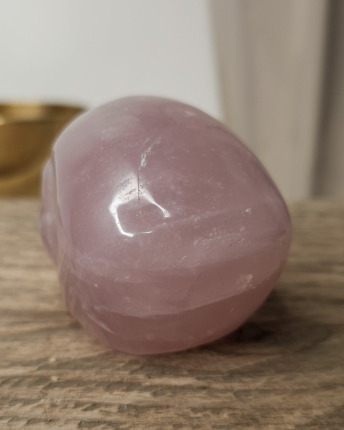 Rose Quartz crystal skull carving with soft pink tones and natural cloudy patterns, polished finish, displayed as a decorative crystal piece.