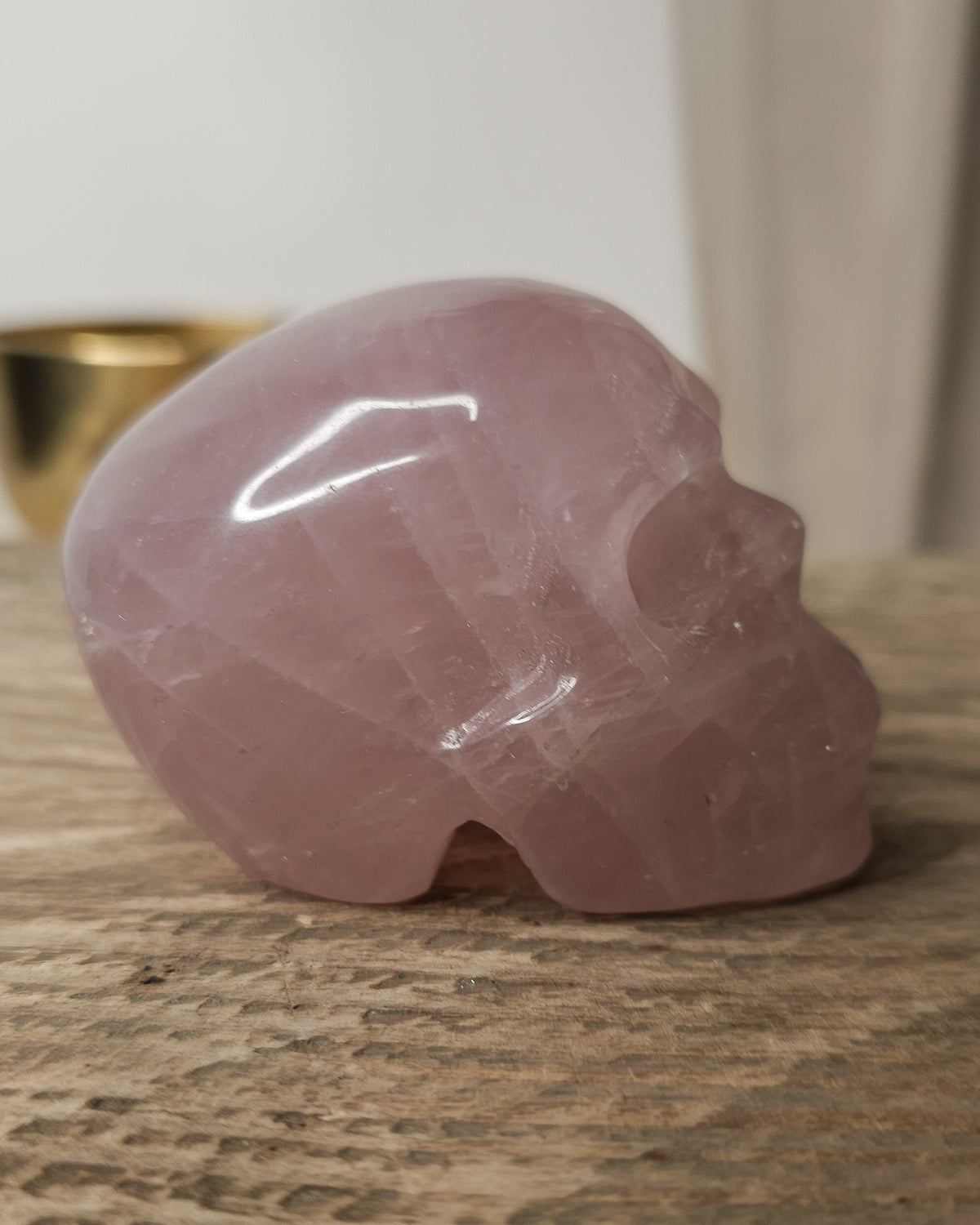 Rose Quartz crystal skull carving with soft pink tones and natural cloudy patterns, polished finish, displayed as a decorative crystal piece.