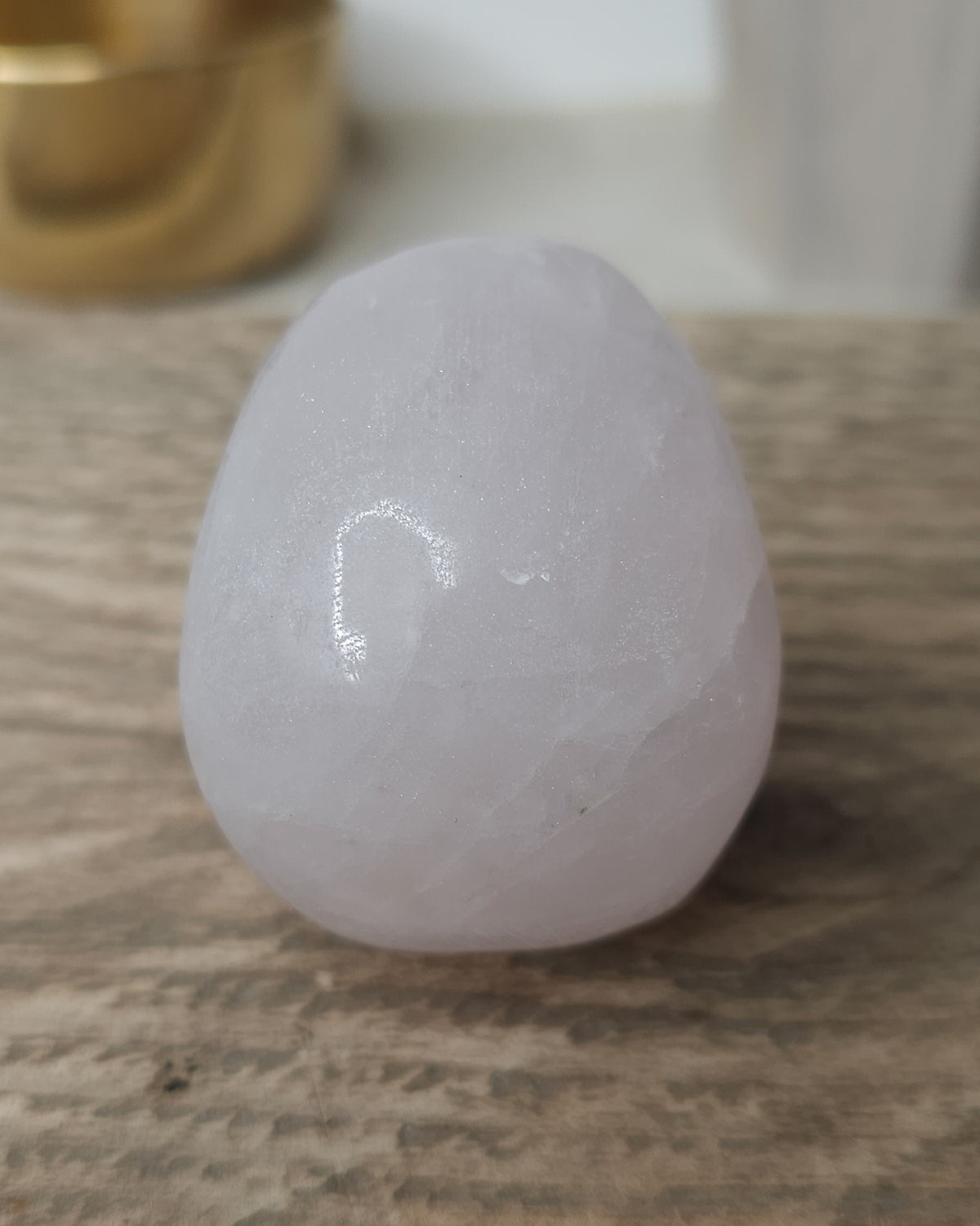 Rose Quartz crystal skull with natural red Hematite inclusions, showing soft pink tones and a reddish patch at the base.