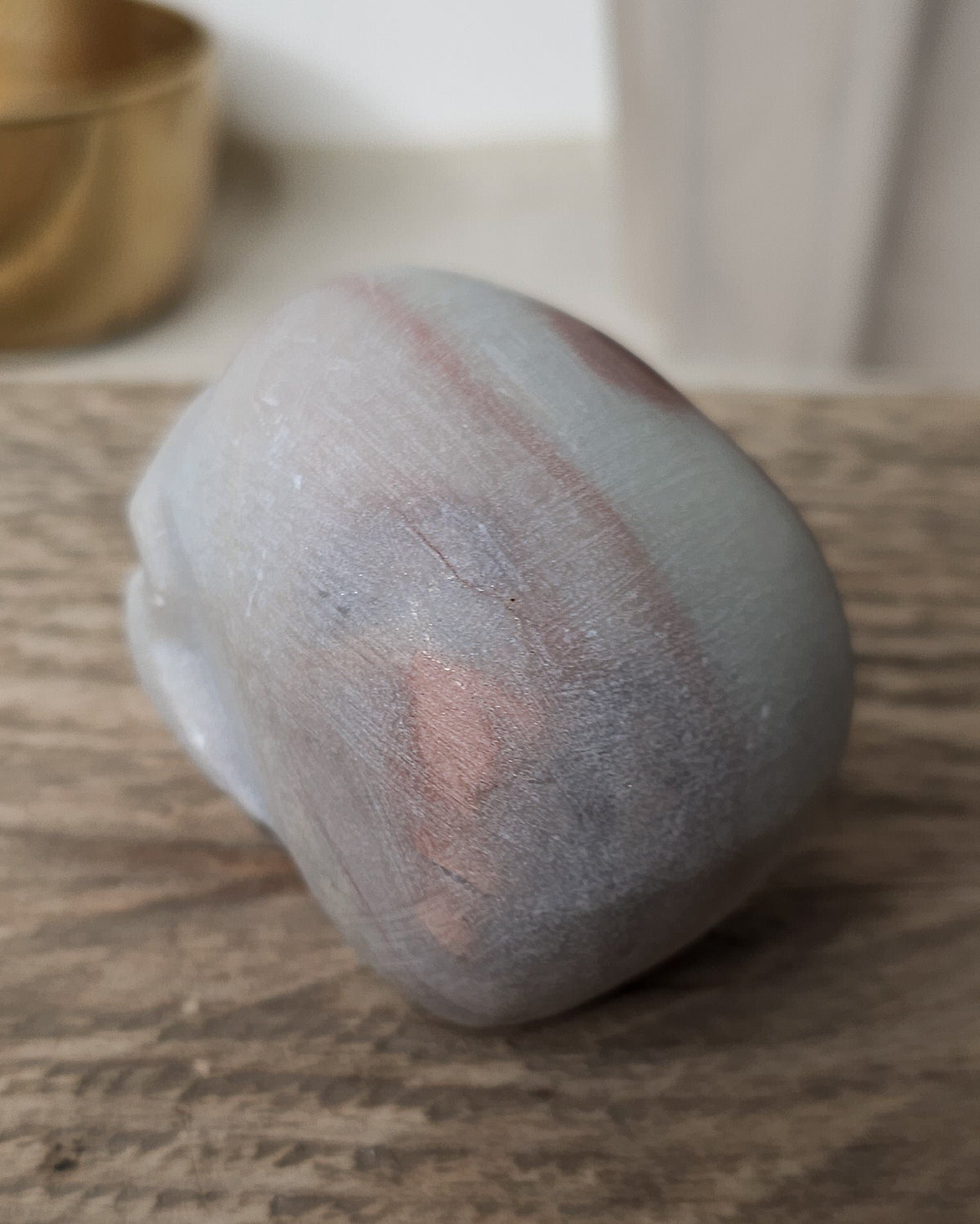Mookaite crystal skull carving with natural burgundy, dusty pink, cream and grey patterns, polished finish and detailed teeth.