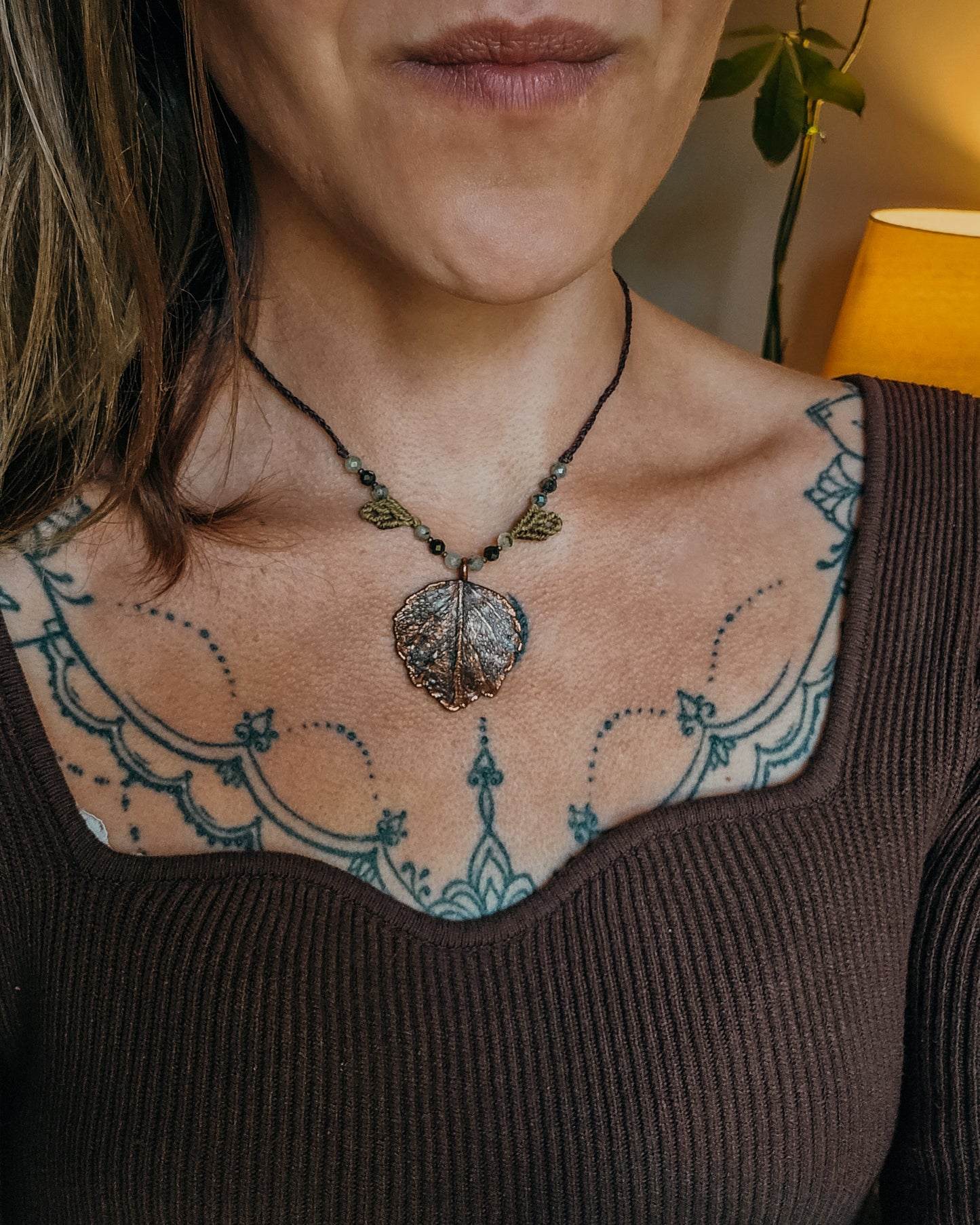 Woman wearing Nettle Spirit Scottish Botanical Amulet, a copper electroformed dead nettle leaf necklace featuring Prehnite with Epidote beads.