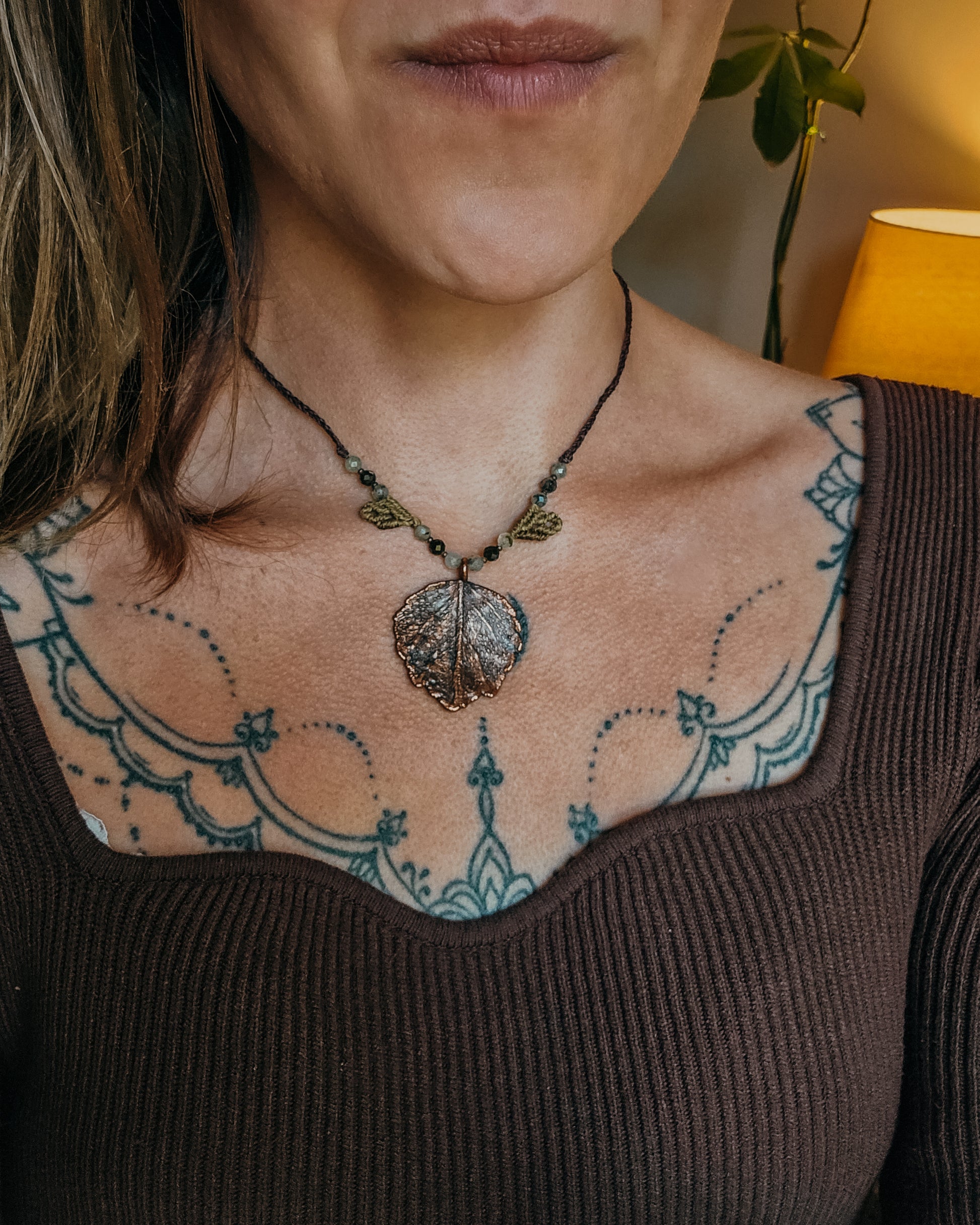 Woman wearing Nettle Spirit Scottish Botanical Amulet, a copper electroformed dead nettle leaf necklace featuring Prehnite with Epidote beads.