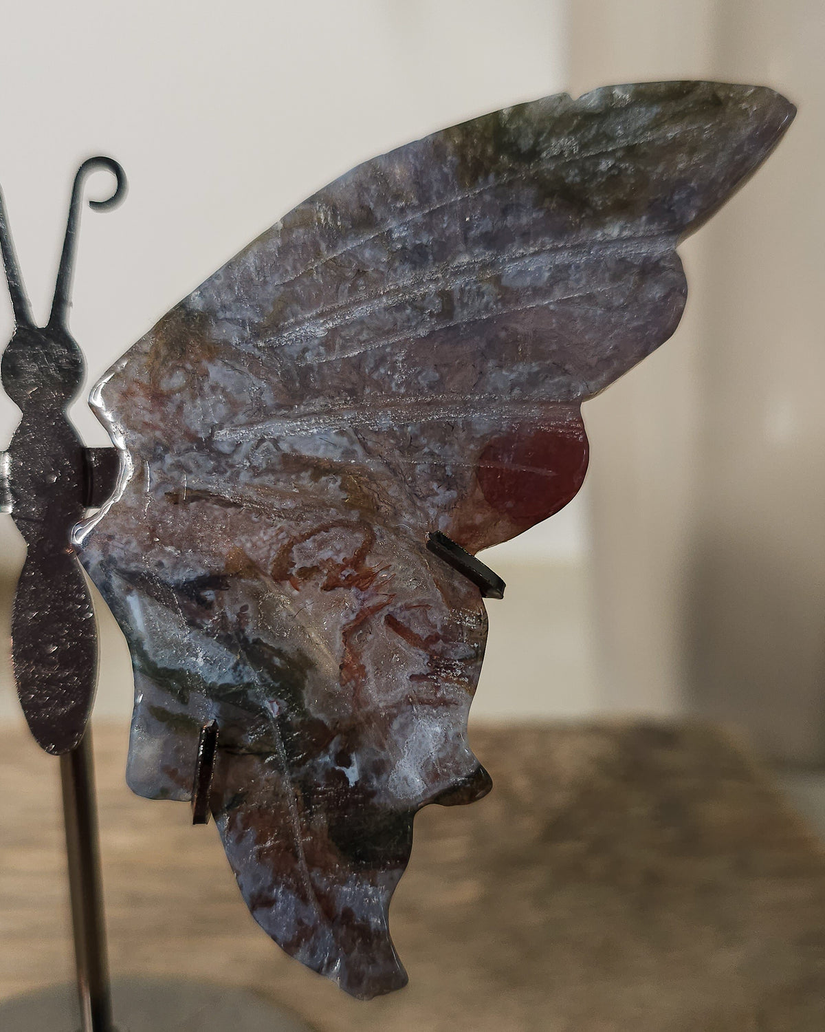 Moss Agate butterfly wings on a black metal stand, featuring natural grey, green, brown and reddish patterns.