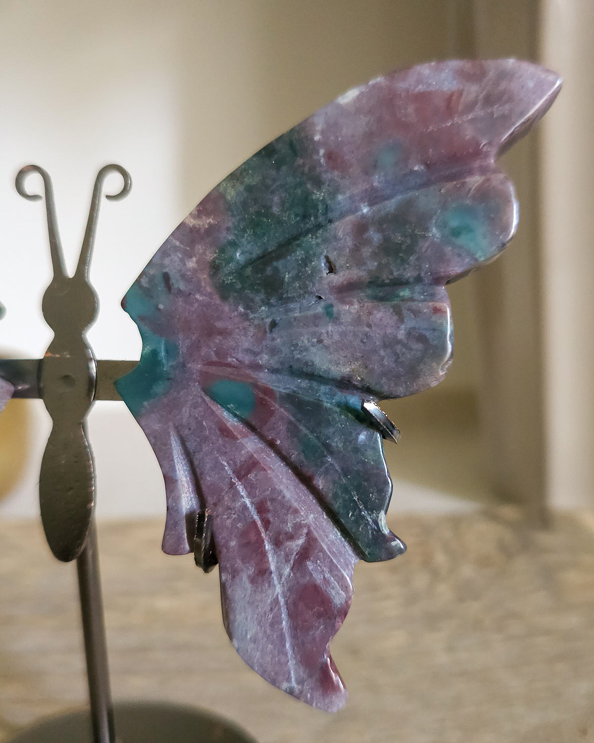 Jasper butterfly wings on a black metal stand, showing natural mauve, pink, green, turquoise and white patterns.