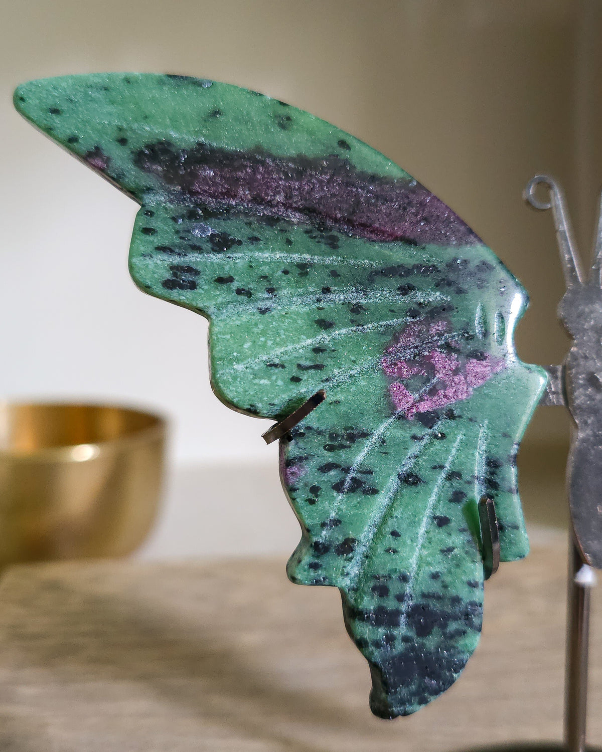 Ruby in Zoisite butterfly wings with fluorescent Ruby inclusions on a black metal stand, glowing vivid pink-red under UV light.
