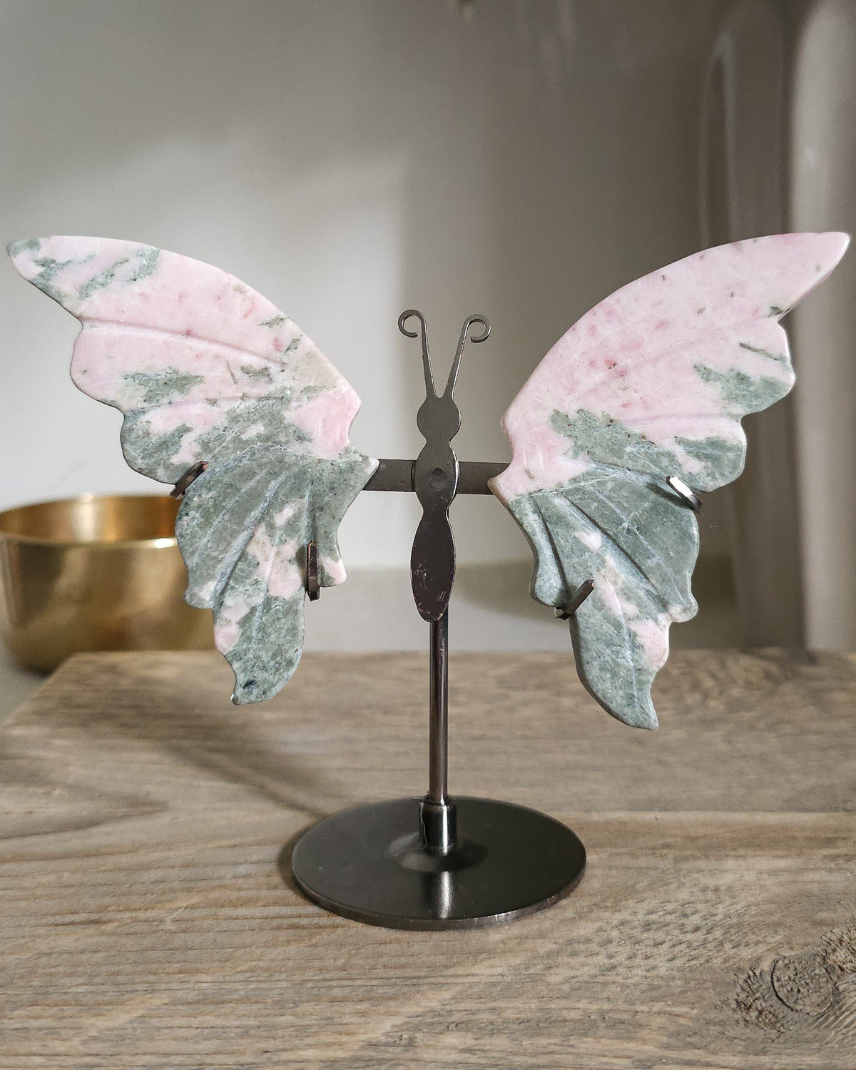 Pink Opal butterfly wings carved from natural pink opal, displayed on a black metal stand, showing soft pink and creamy tones.