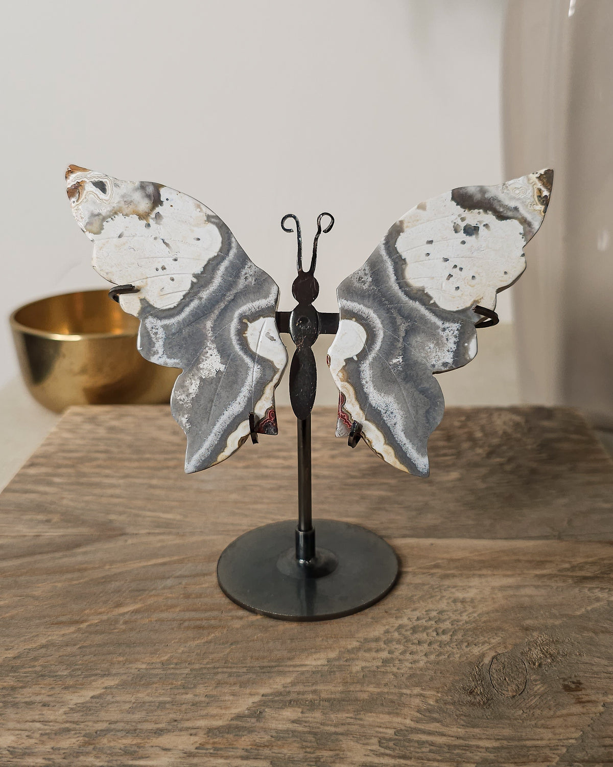 Grey and white Agate butterfly wings displayed on a metal stand, featuring soft natural banding and cloudy patterns.