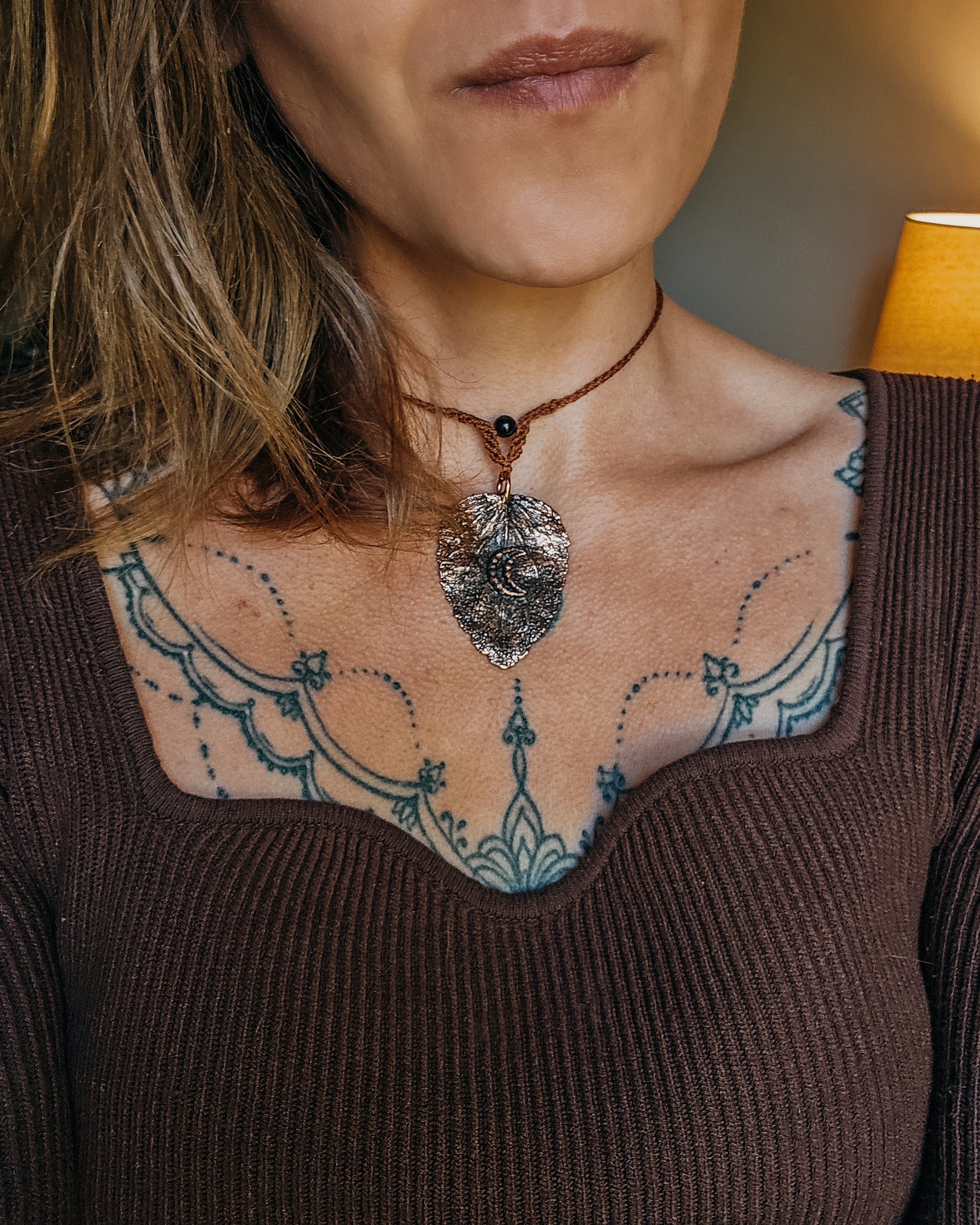 Woman wearing Nettle Spirit Scottish Botanical Amulet, a copper electroformed dead nettle leaf necklace with Golden Sheen Obsidian.
