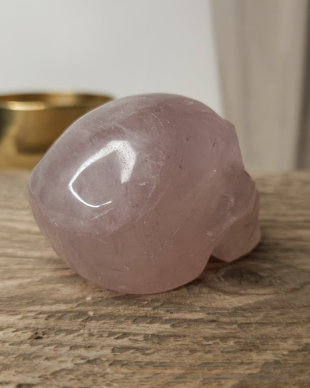 Rose Quartz crystal skull carving with soft pink tones and natural cloudy patterns, polished finish, displayed as a decorative crystal piece.